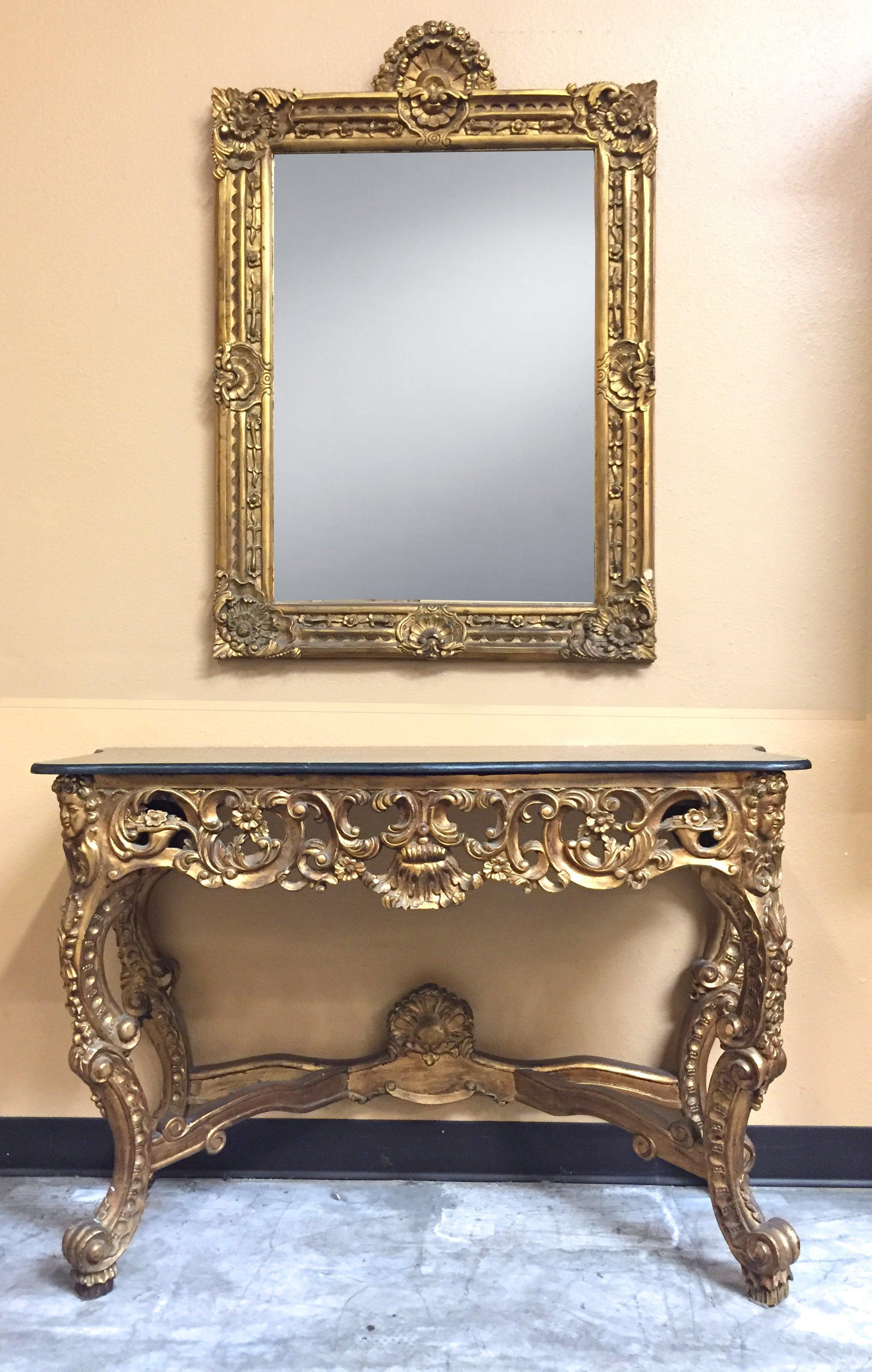 Console et miroir italien en bois doré magnifiquement sculpté avec dessus en marbre noir.
Début du 20e siècle. 

Le miroir est surmonté d'une coquille dorée, au-dessus d'une plaque de miroir rectangulaire entourée d'un cadre sculpté dans un motif