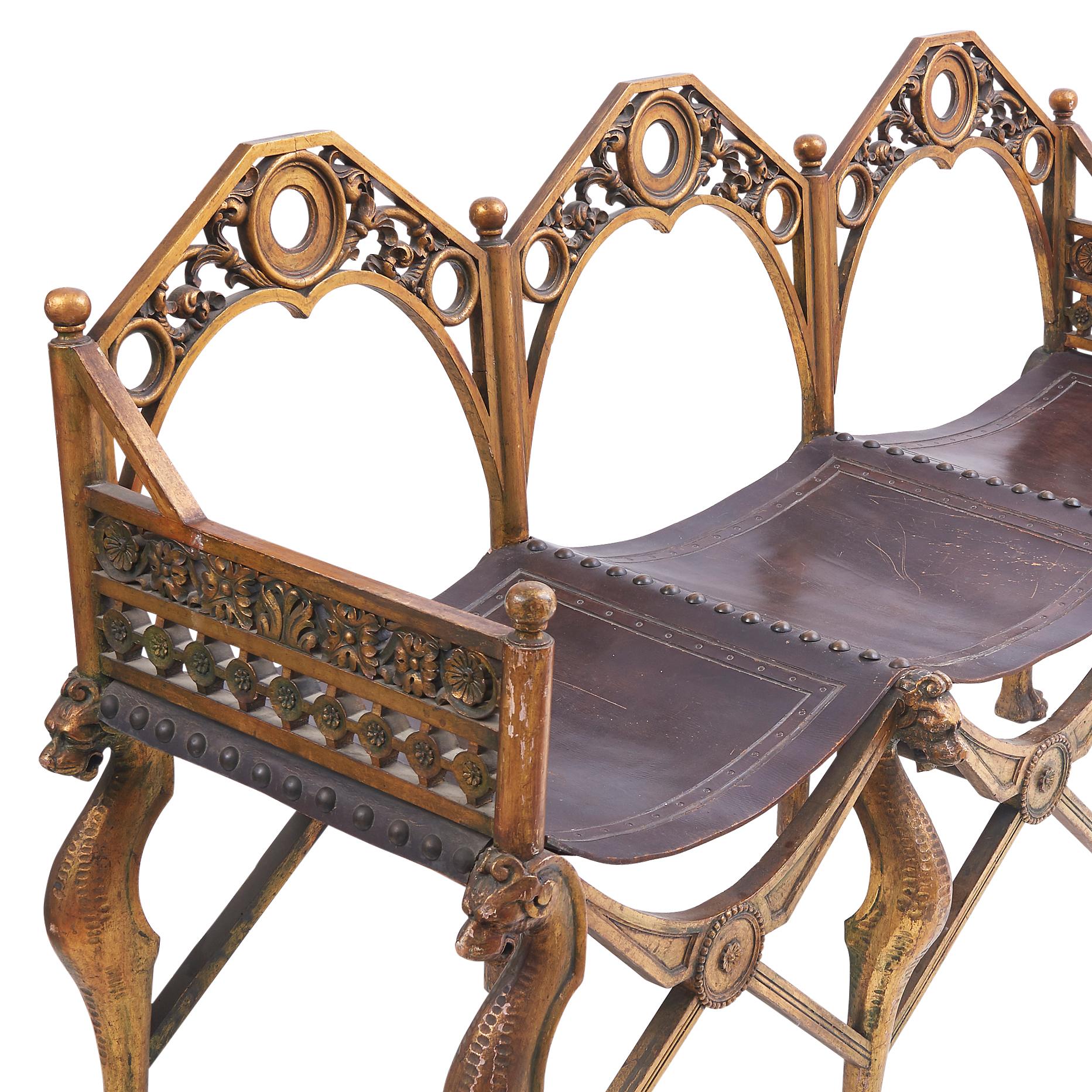 An Italian carved triple back sofa with a matching armchairs, c1910. The giltwood frames in a gothic, grotto style, with scrolling and floral decoration to the back and arms. The legs with carved dragons and x frame stretchers, supporting leather