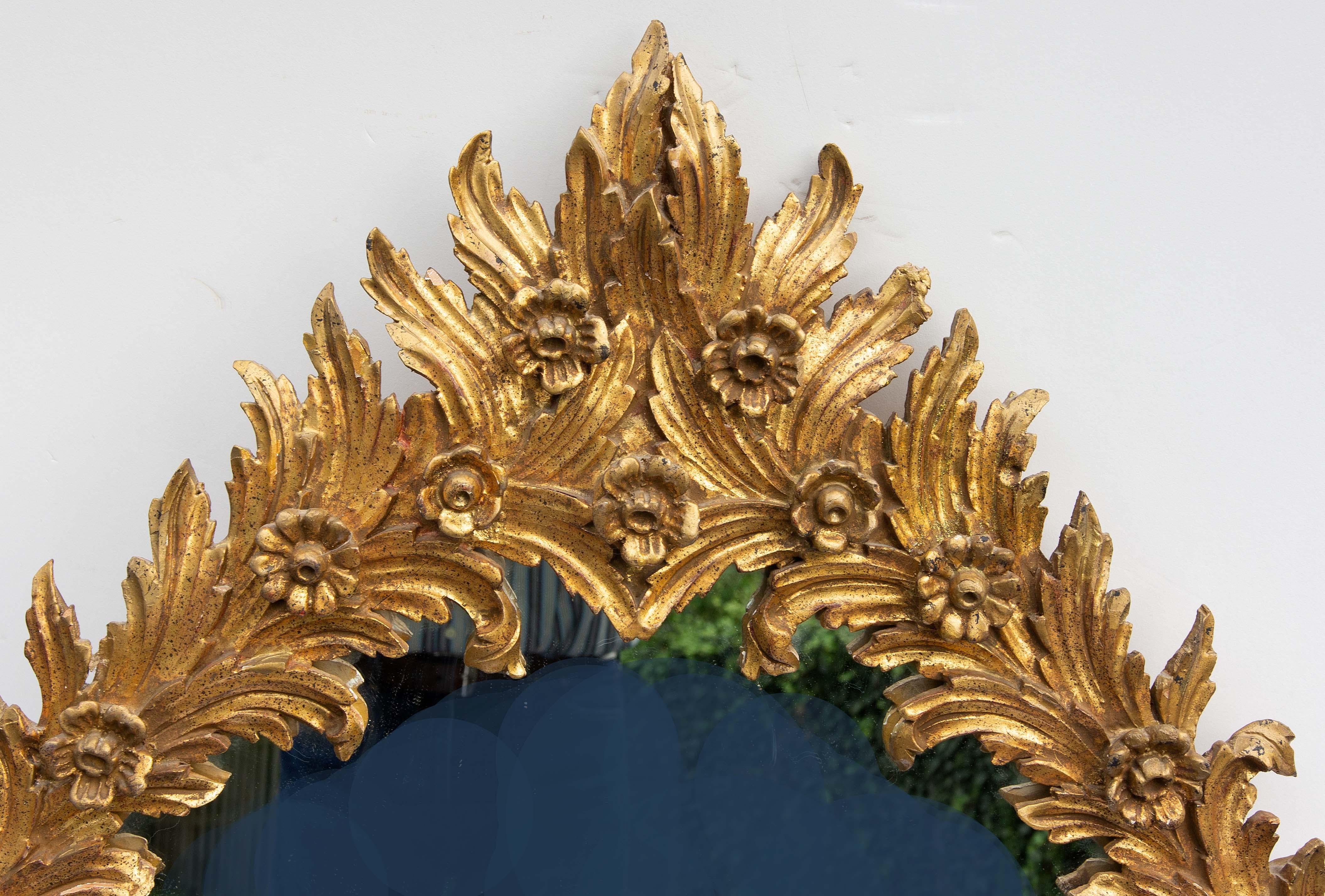 Miroir italien en bois doré. Sculptée de flammes et de fleurons stylisés. Milieu du 20e siècle. Veuillez nous contacter pour les options d'expédition.