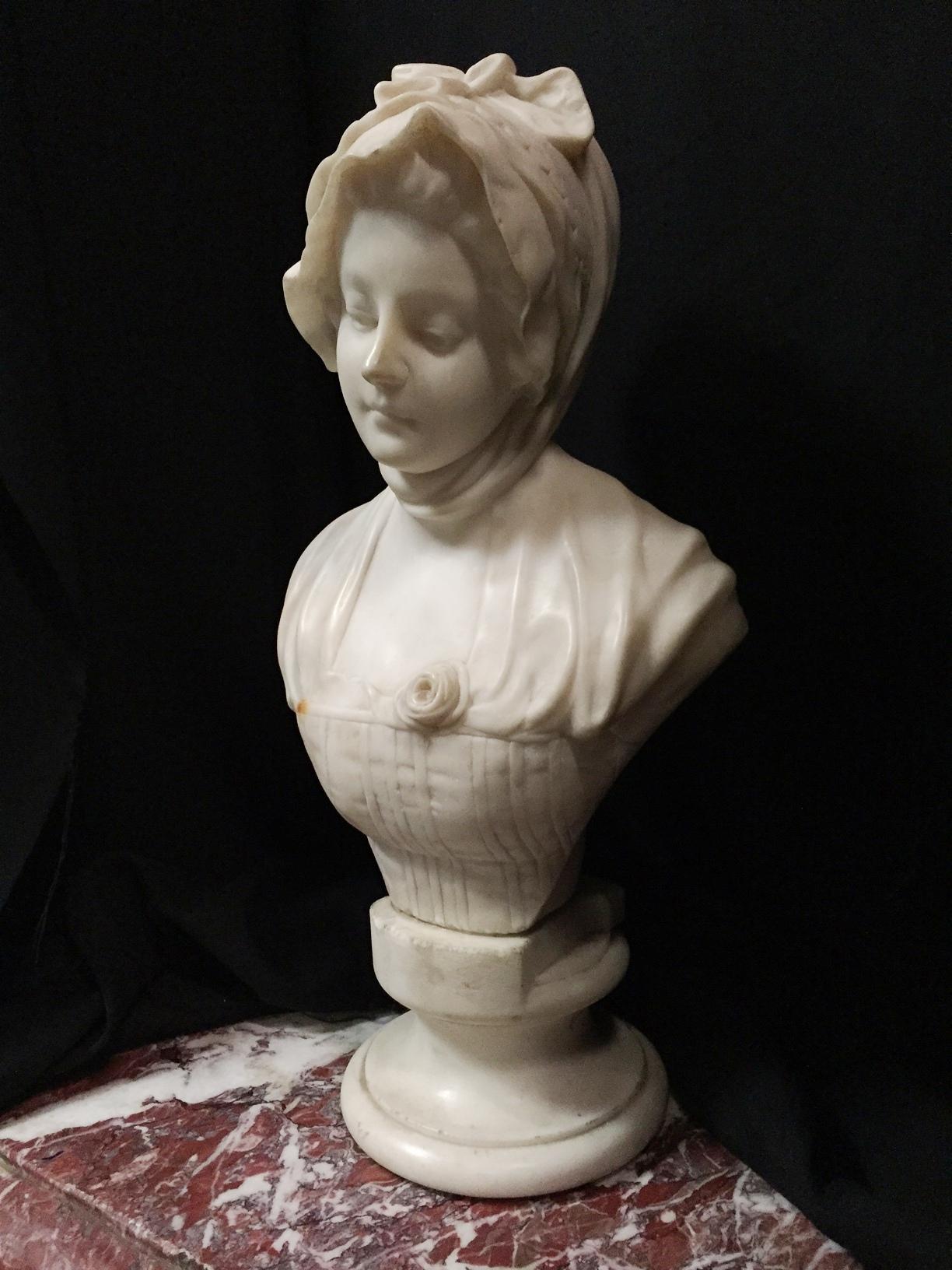 19th century Italian carved marble bust of a maiden in classical robes and headdress. Meticulous attention is given to the details of the bust and especially on the facial features.

Measures: Diameter of base: D. 7
