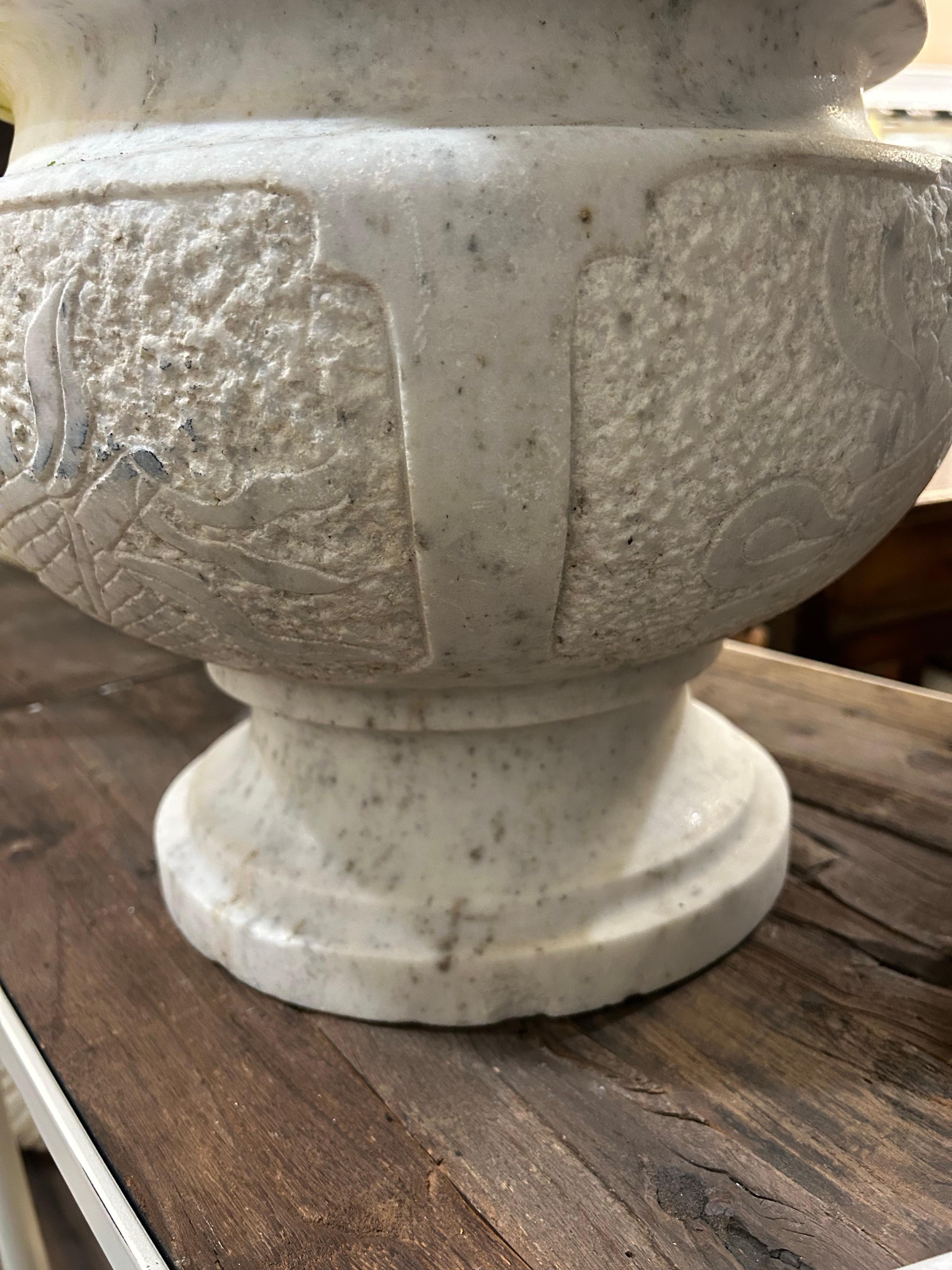 Se trata de una urna italiana de mármol Carrera de principios del siglo XX. Mide aprox. 13,5 pulgadas de diámetro y 12 pulgadas de alto  Hay un desconchón en el borde y un par de desconchones en la base de pie redondo... Hay cuatro paneles tallados