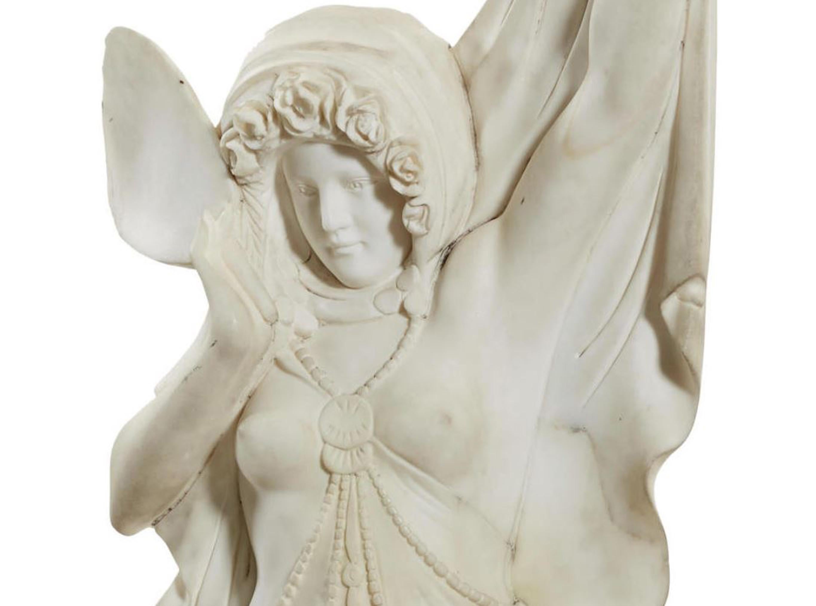 Life-size monumental Italian hand carved white marble statue of a standing maiden. 
The attractive semi-nude maiden is standing in a victorious power stance with her head covered in a hood and wearing a Classical robe, raised on a stepped marble