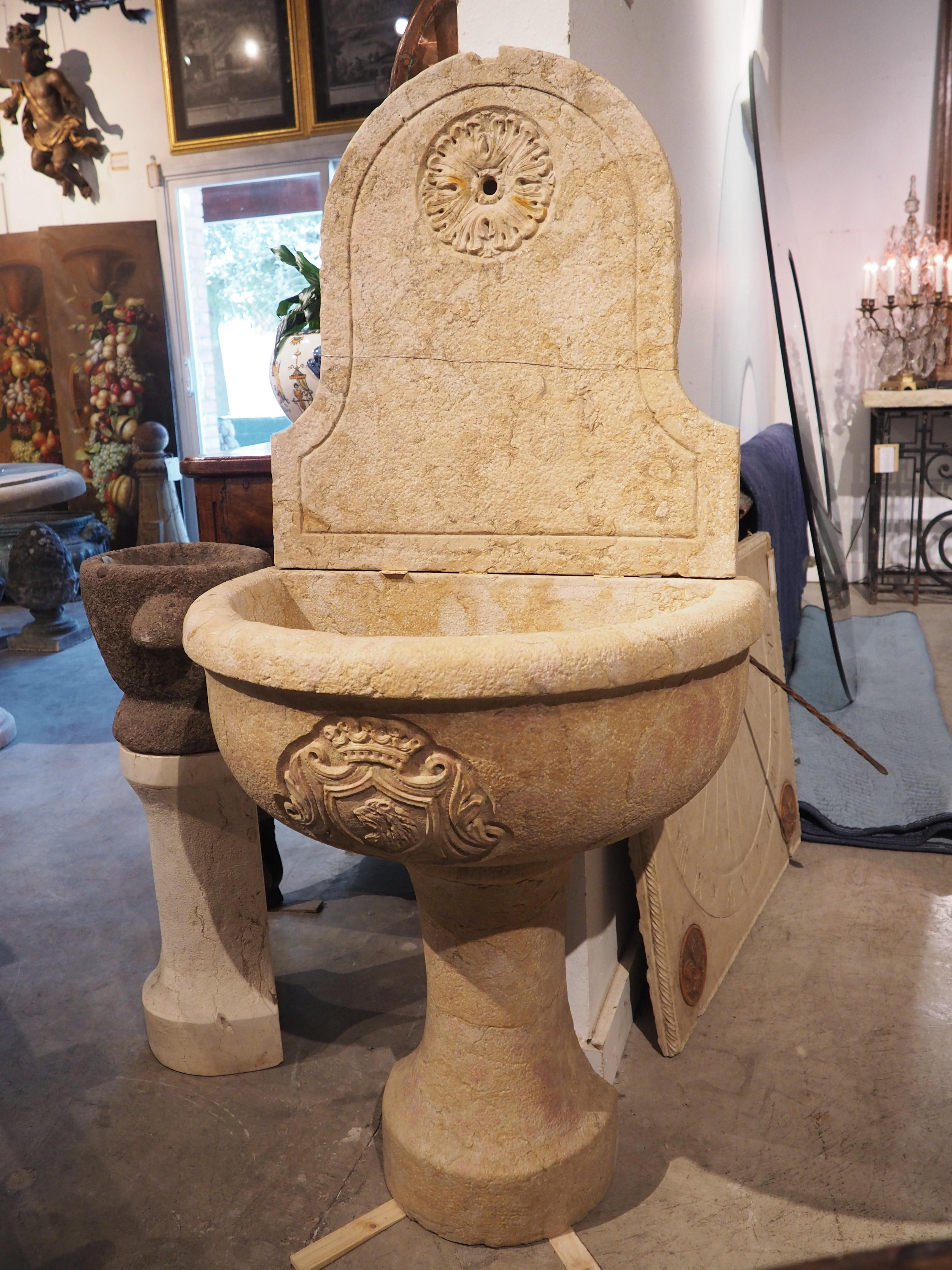 A lovely Italian wall fountain that has been hand-carved from three pieces of marble. The cream-colored stone has subtle brown and gold inclusions. A stout demi-lune basin (8 ½ inches tall) with quarter round edges sits on top of a half pedestal