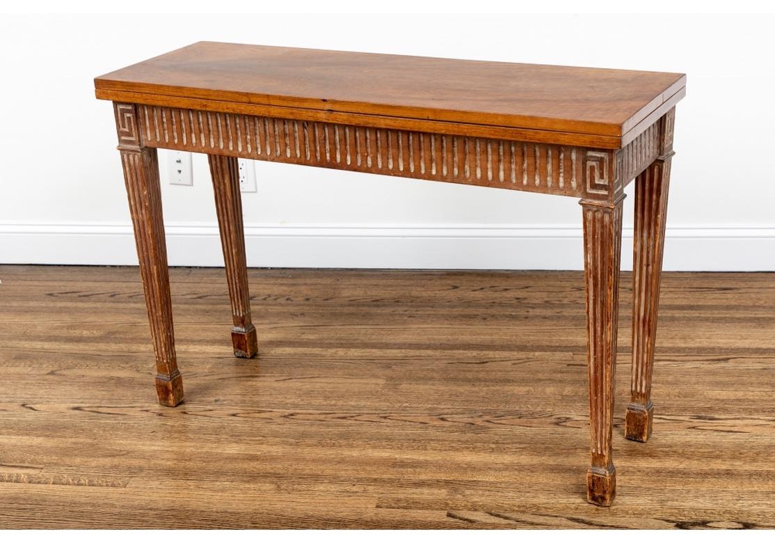 An older rectangular console table with particularly fine swirly grain carved and in an antiqued finish with limed accents. The fluted apron raised on square tapering fluted legs with block feet, the tops with Greek key motifs. The fine book matched