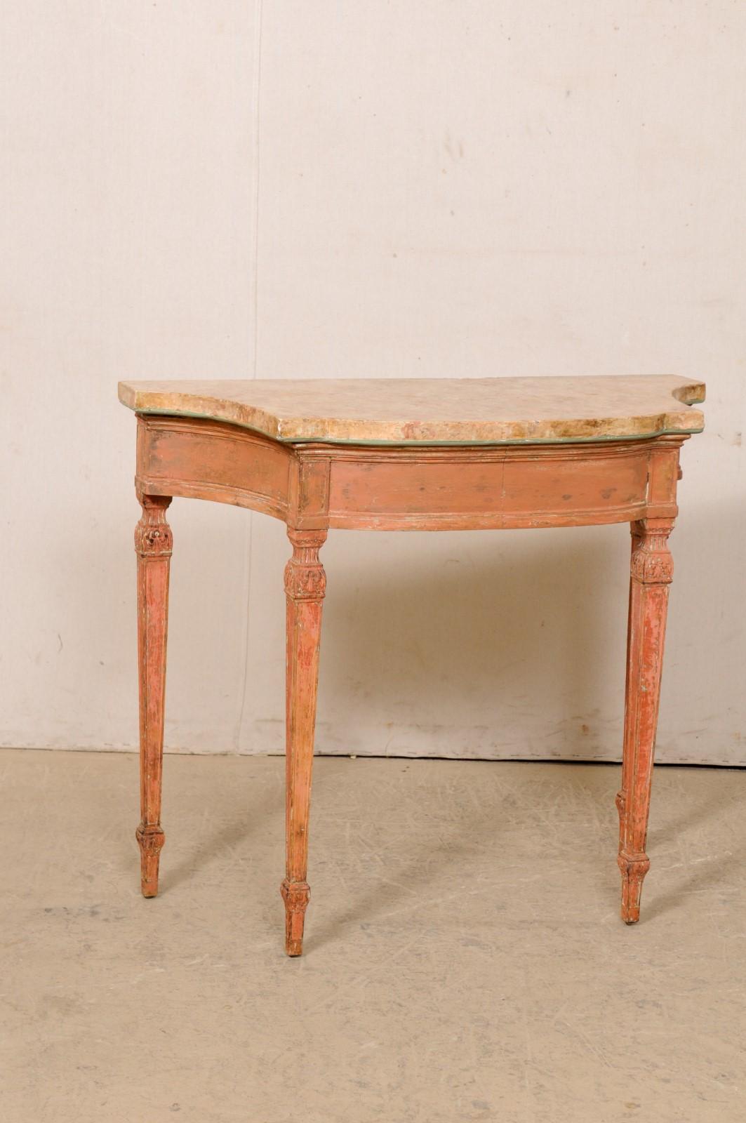 An Italian carved wood console with scagliola top from the turn of the 18th and 19th century. This antique table from Italy features a scagliola top in a lovely warm tan color palette with salmon accents, with a thin trimming of blue green outlining