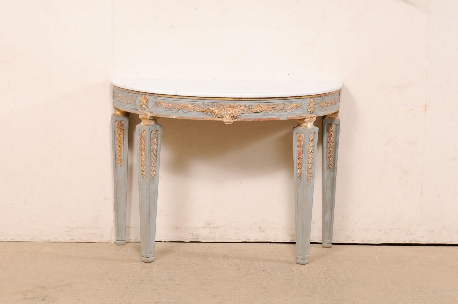 An Italian painted wood demi-lune table with marble top. This vintage table from Italy features a half-moon shaped marble top which rests atop an apron decorated with a bouquet basket of flowers at front center, flanked within a rhythmic display of