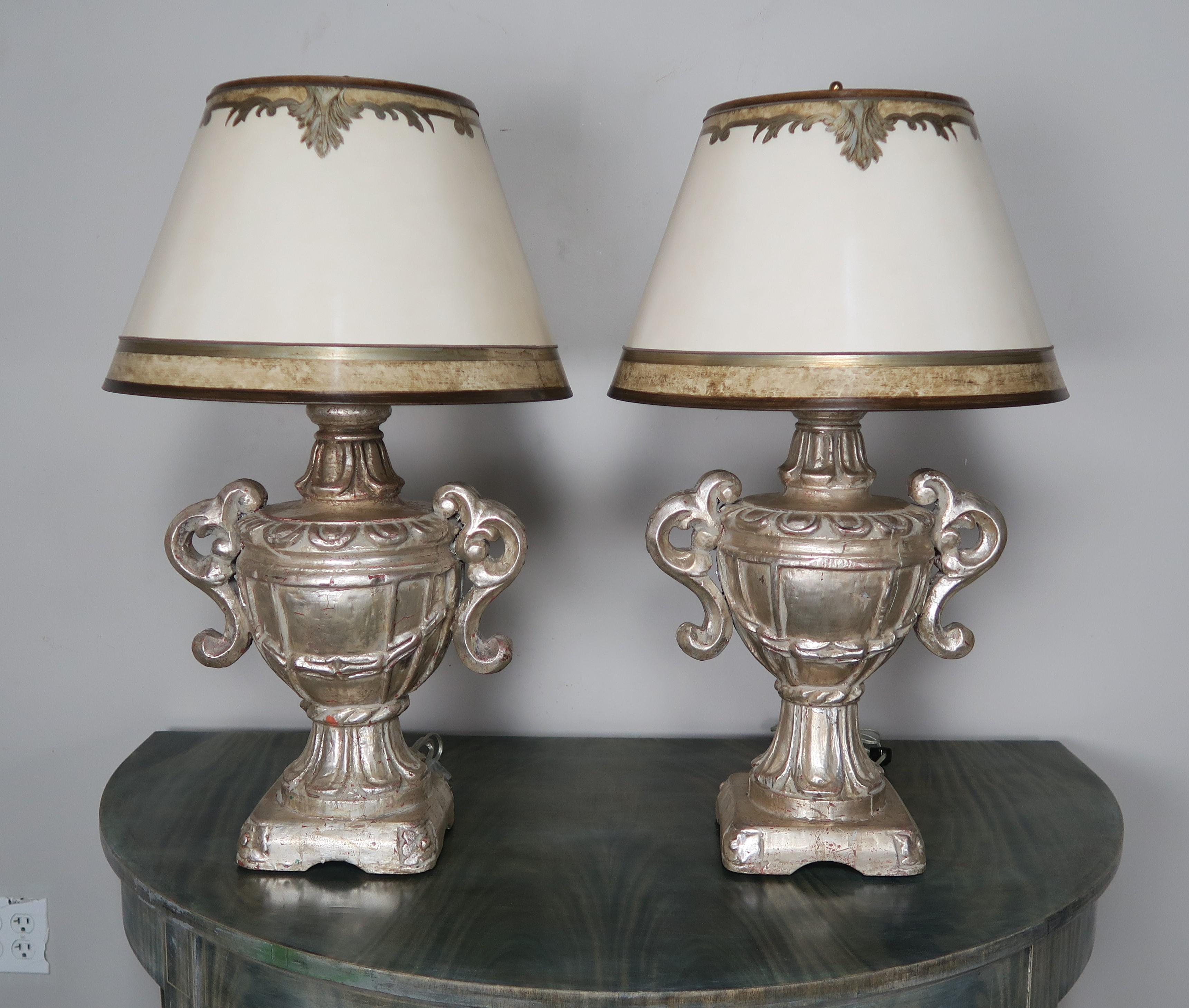Italian carved wood silvered urn lamps with custom hand-painted parchment shades. The silver urns have been newly rewired and are in working condition.