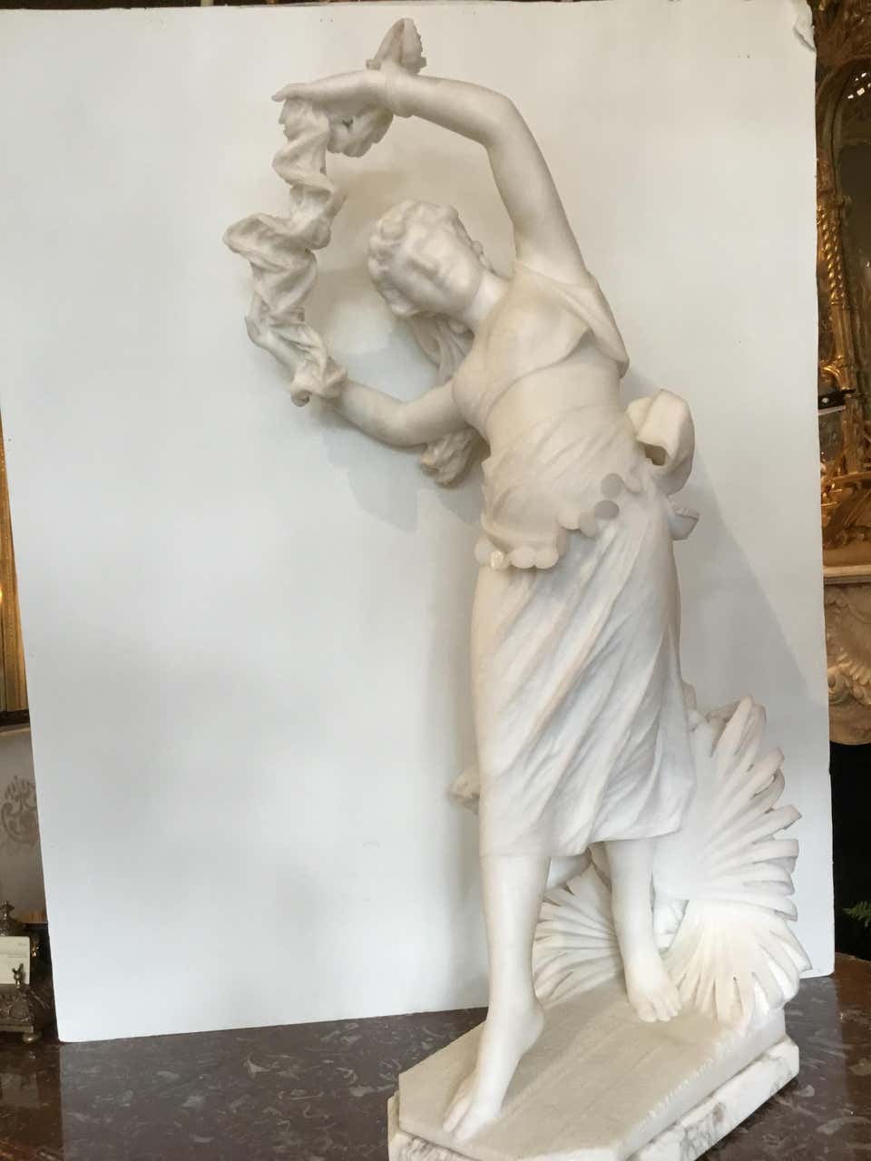 Turkish dancing girl with a bare midriff, a scarf in her hand,
Her skirt hung with jangling coins with well carved
Palmettos in the background.