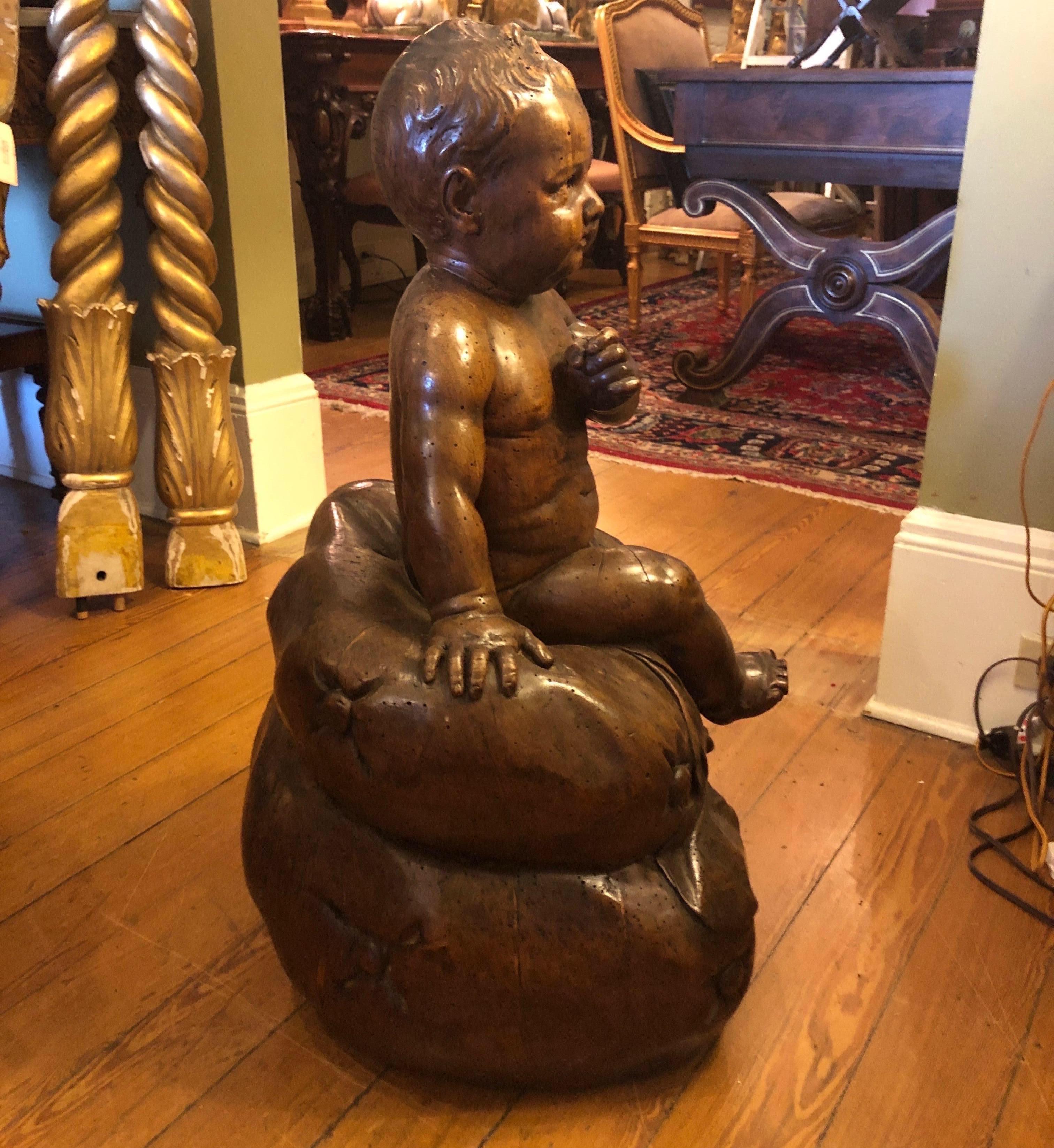 Italian baby figure sitting on a cushion carved of walnut. Expected losses and repairs. See photos all are highlighted.
  