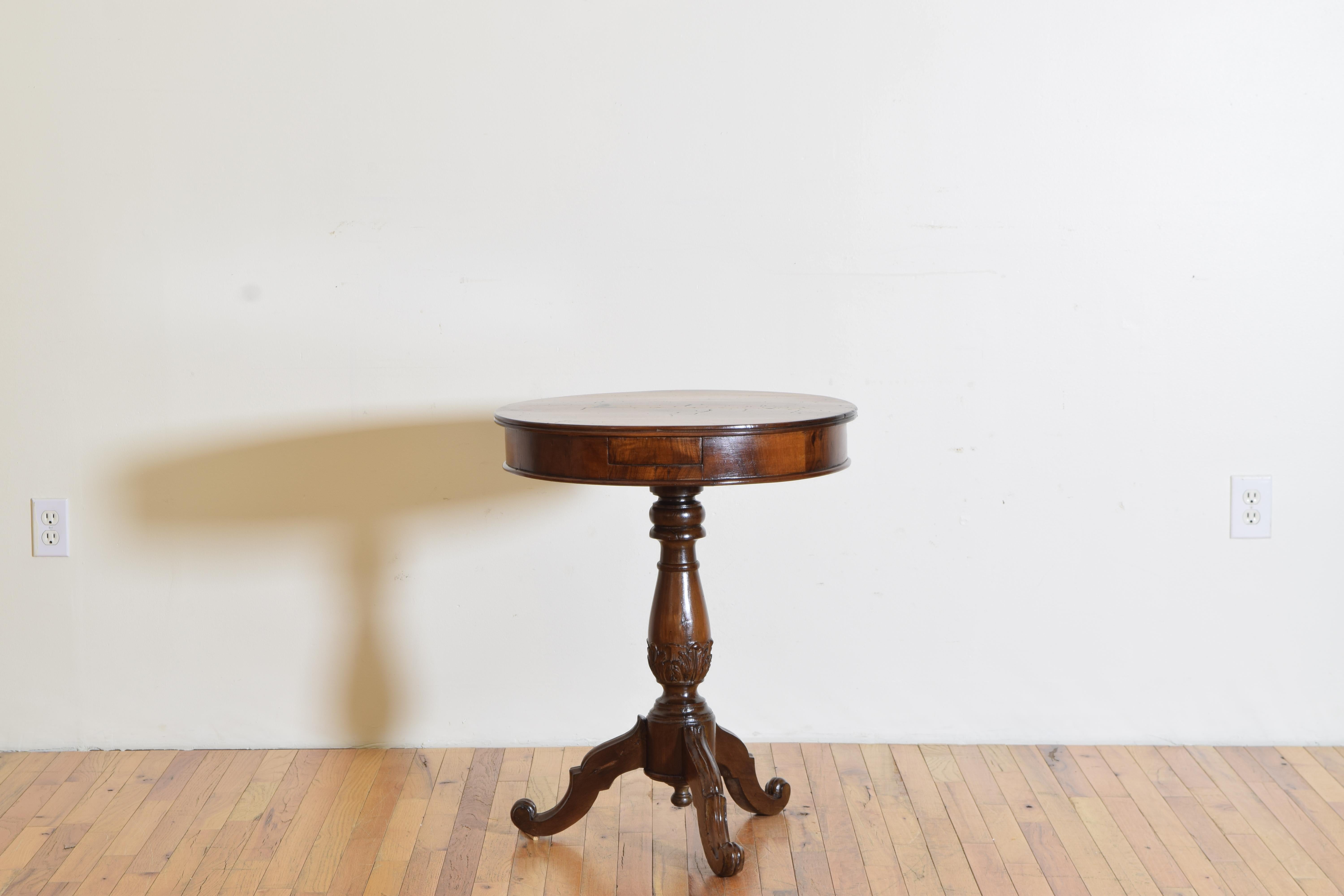 A round walnut side table with an interesting pop-out drawer accessed by a button under the tabletop raised on a carved pedestal ending on a carved tripod footed base.