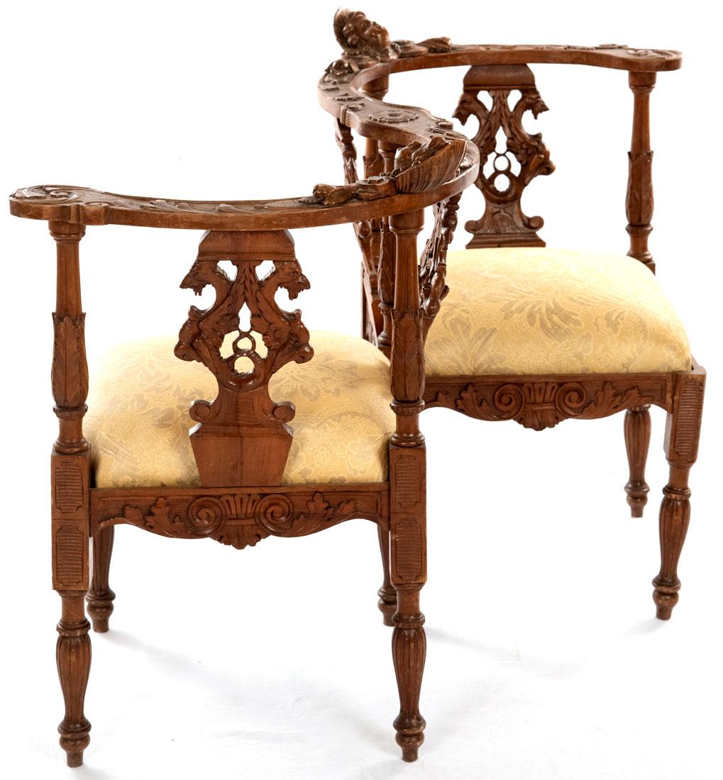 A Venetian-style, Renaissance Revival conversation chair in carved walnut with silk upholstery.