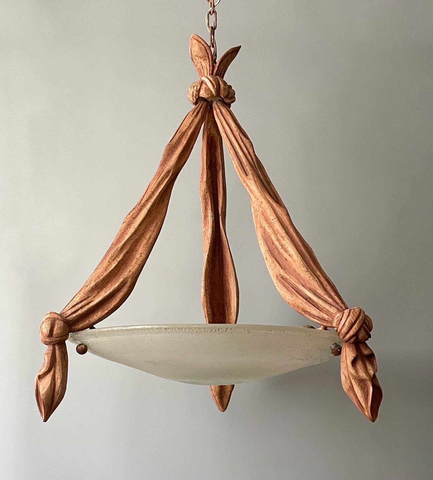 Fantastic, Italian vintage chandelier in the Hollywood Regency manner.

The chandelier features carved and painted wood supports simulating three draped scarves suspending a Murano glass shade executed in the scavo-corroso technique. 

The