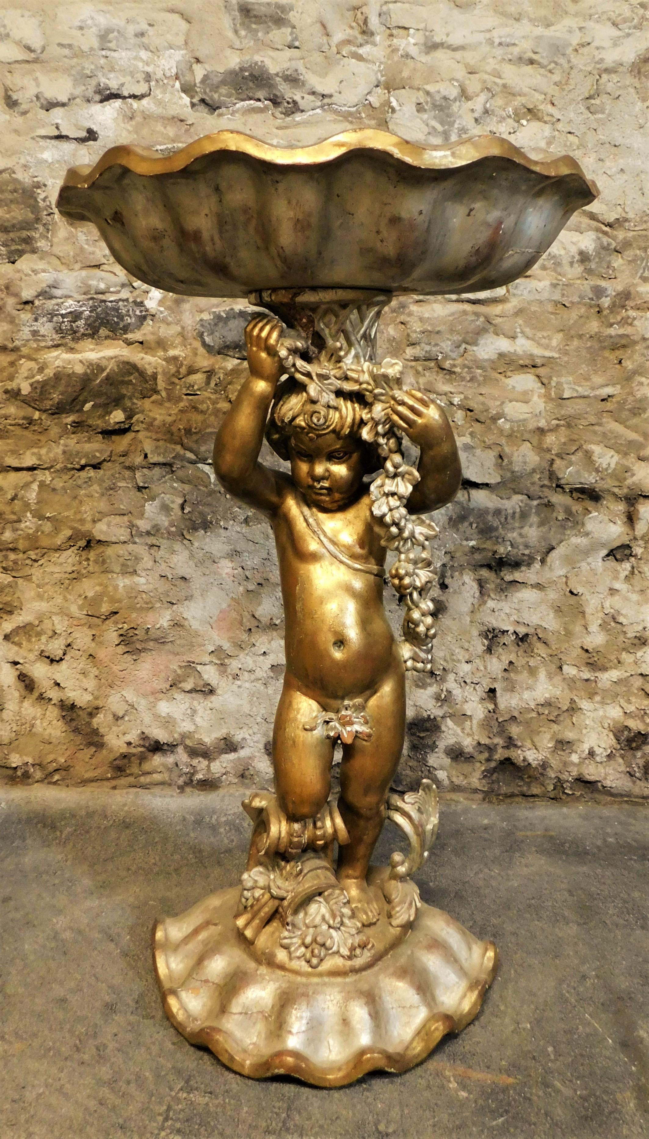 Beautiful large Italian carved wooden bird bath or garden planter of a cherub/child holding a sea shell with a shell base. Nice patina on the copper plate insert on the top holding shell and is nicely painted. Lots of small chips, small crack, paint
