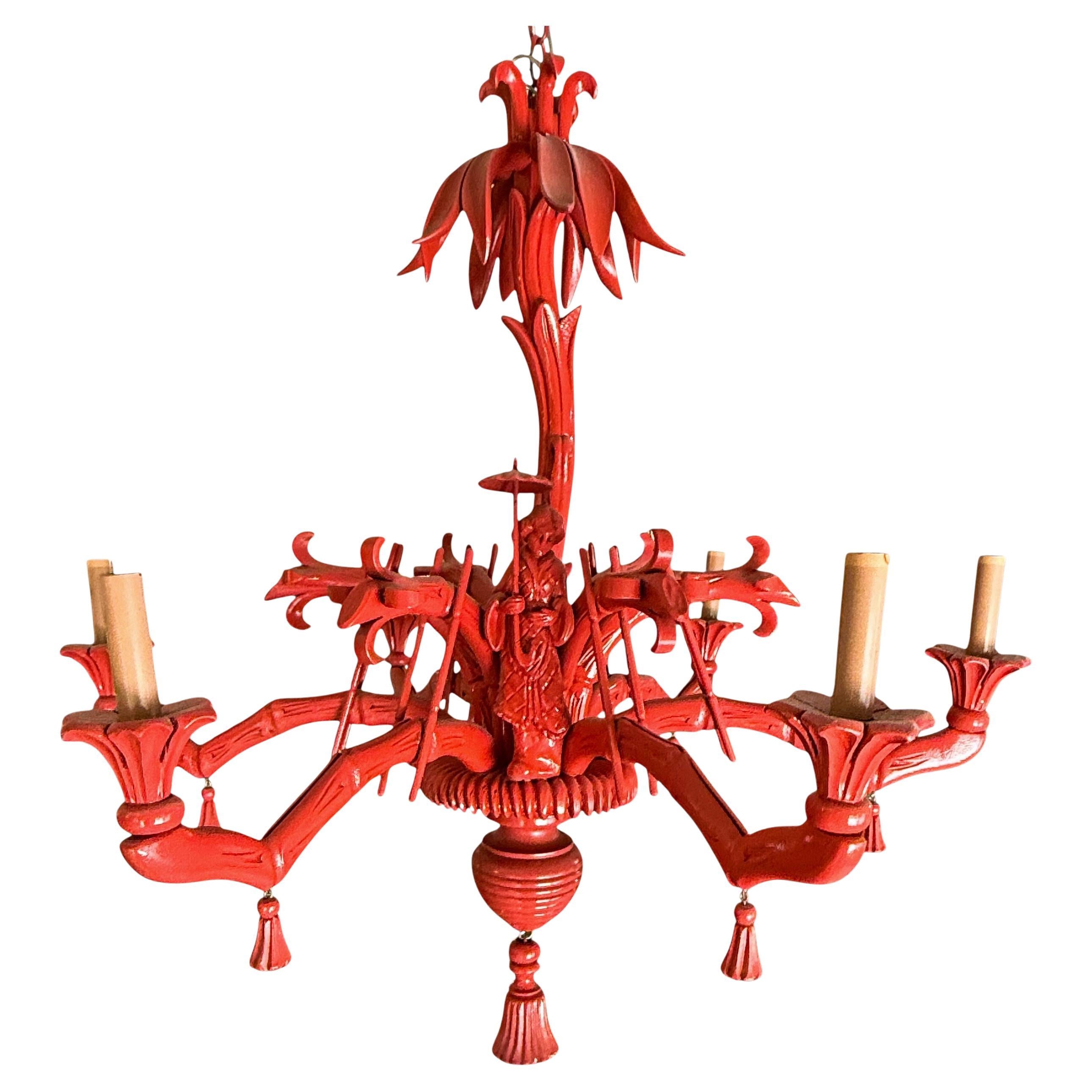 Si tratta di un lampadario italiano a cineserie in legno intagliato con bracci in finto bambù e fronde di palma intagliate. Ha sei braccia e nappe lungo tutto il pezzo. La lacca cinese rosso/corallo non è originale. Ha una fanciulla asiatica che