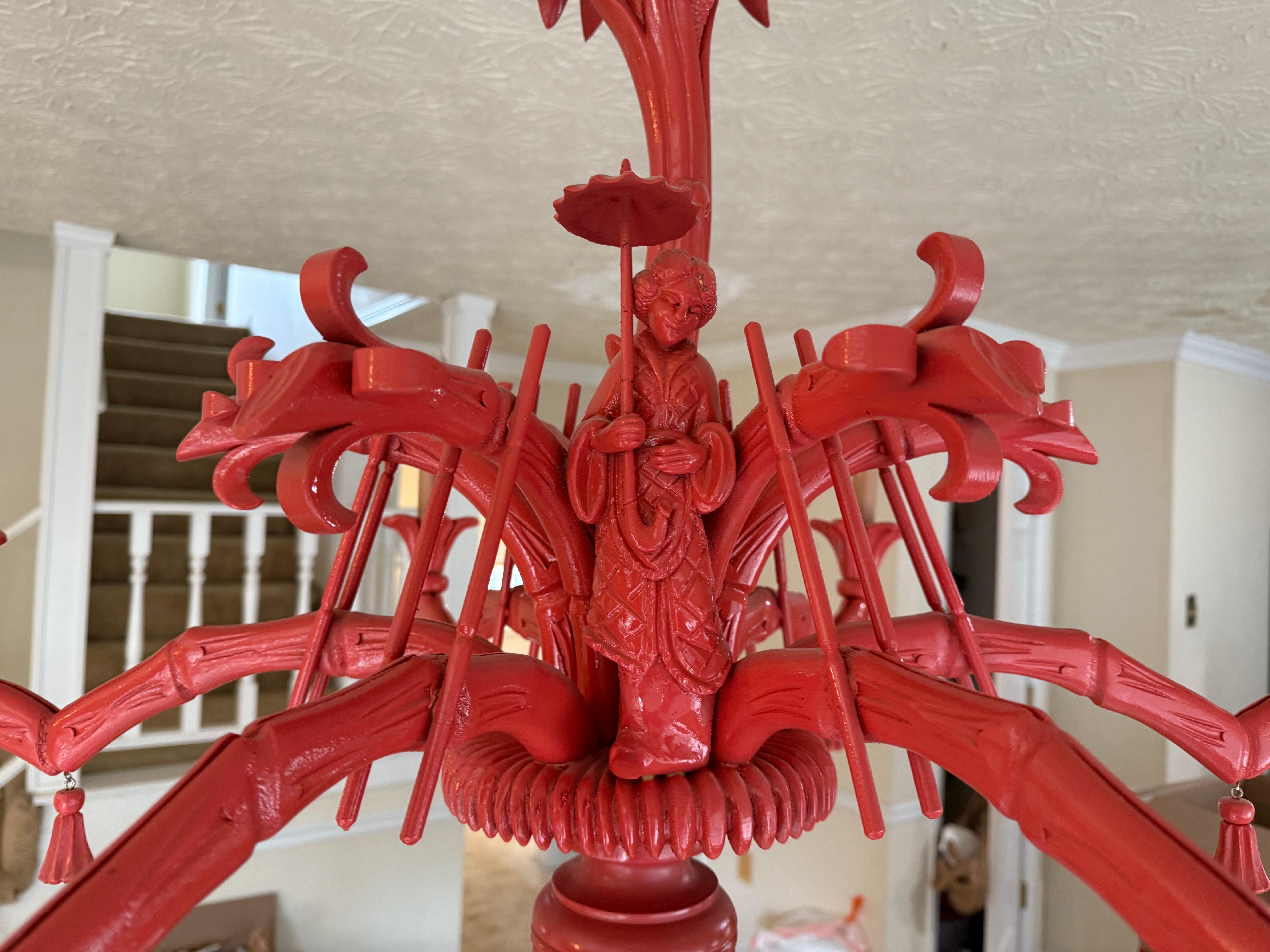 Se trata de una lámpara de araña chinesca italiana de madera tallada, con brazos de bambú de imitación y palmas talladas de apoyo. Tiene seis brazos y borlas por toda la pieza. La laca china roja / coral no es original. Tiene una doncella asiática