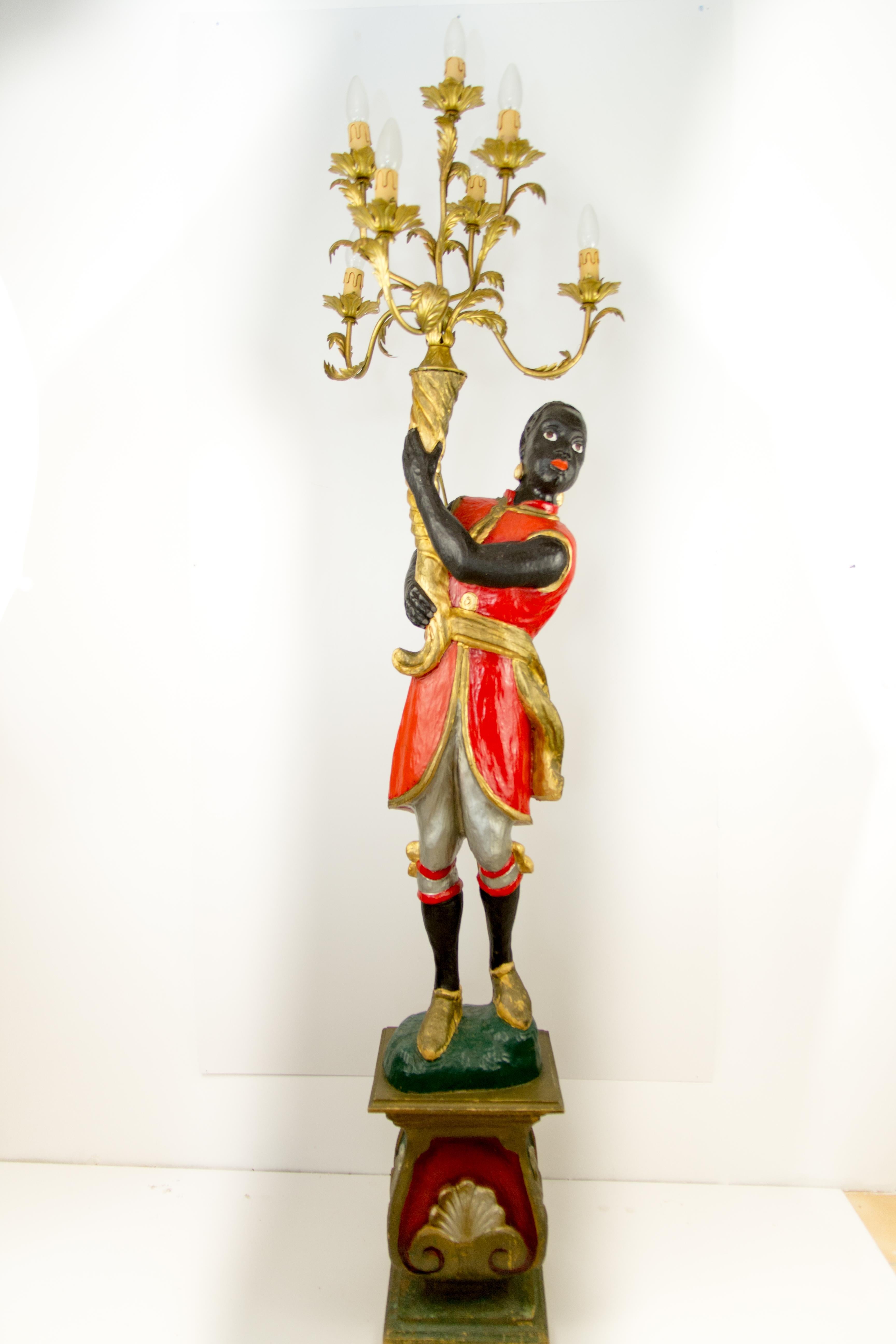A beautiful and colorful Italian floor lamp is made of carved wood and the polychrome painted figure is holding a seven-arm candelabra. Each arm of golden color tole candelabra is decorated with foliage decors and flower-shaped bobeches. The figure