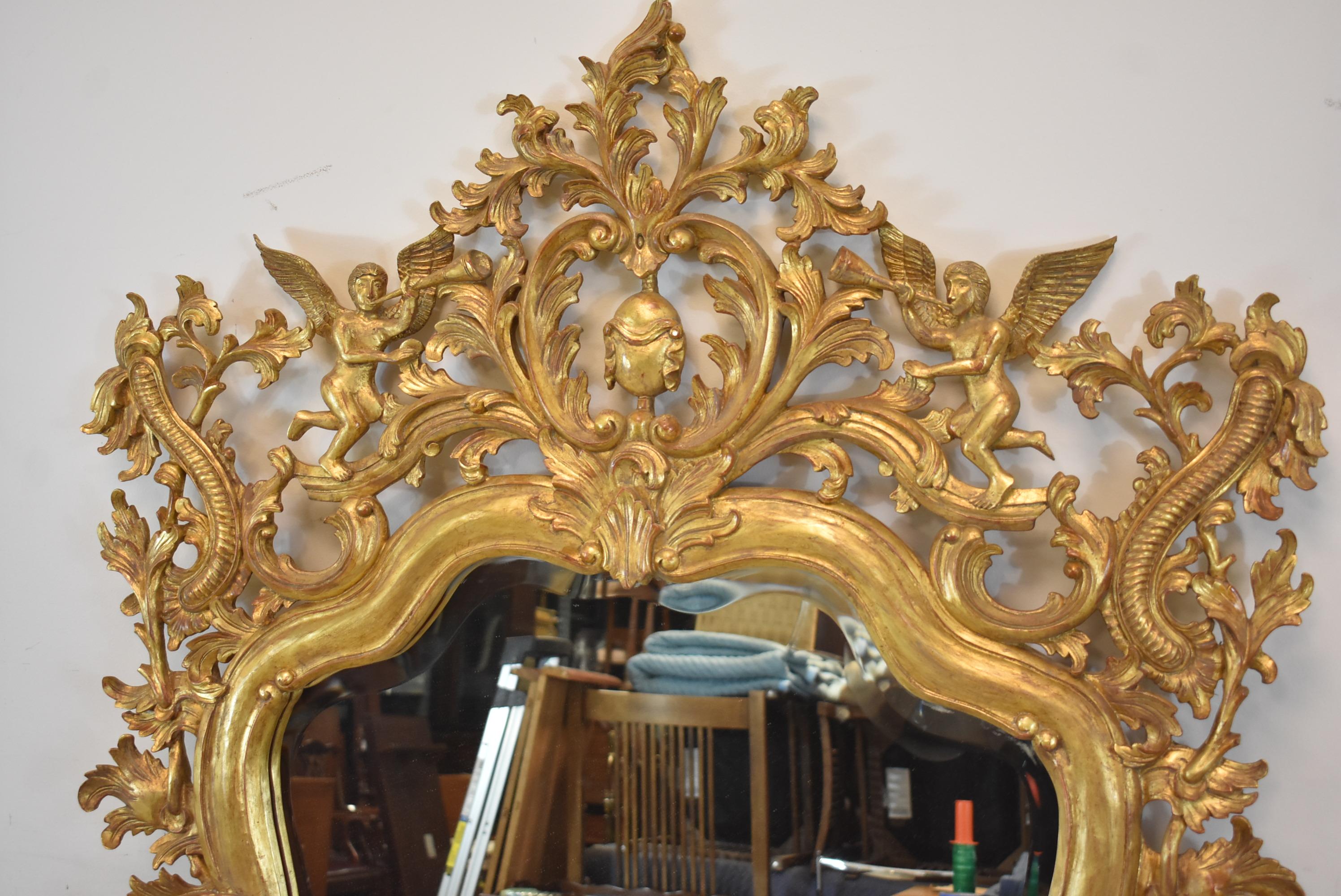 Elaborately carved wood gold gilt Italian framed beveled mirror. Adorned with trumpeting angels and stringed musical instruments. Very nice condition. Dimensions: 3