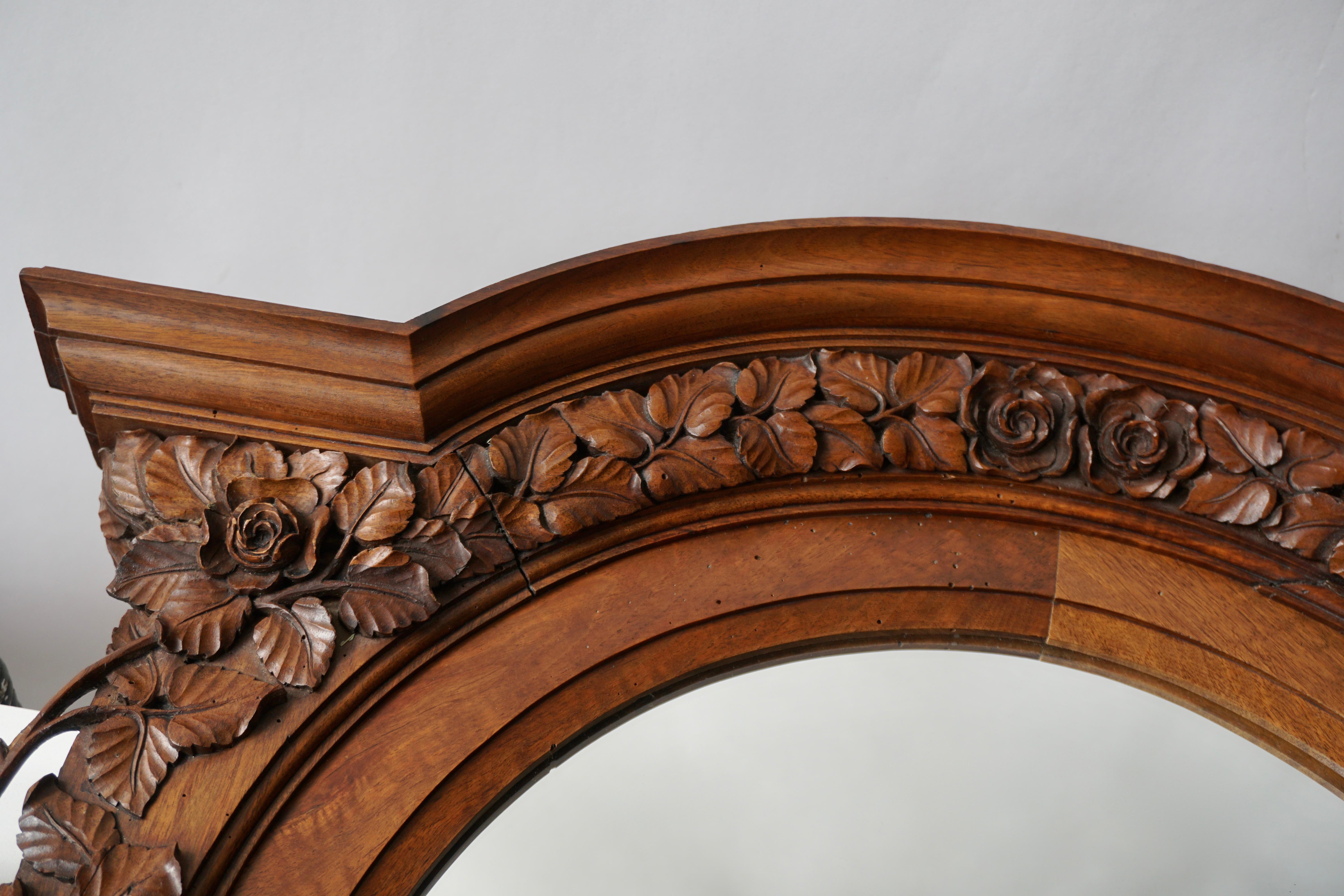 An impressive Italian carved wood wall plaque with center mirror from the early 20th century. This antique wall decoration from Italy features ornate three dimensional hand carvings in a shell, floral, and scrolling leaf motif, about a framed mirror
