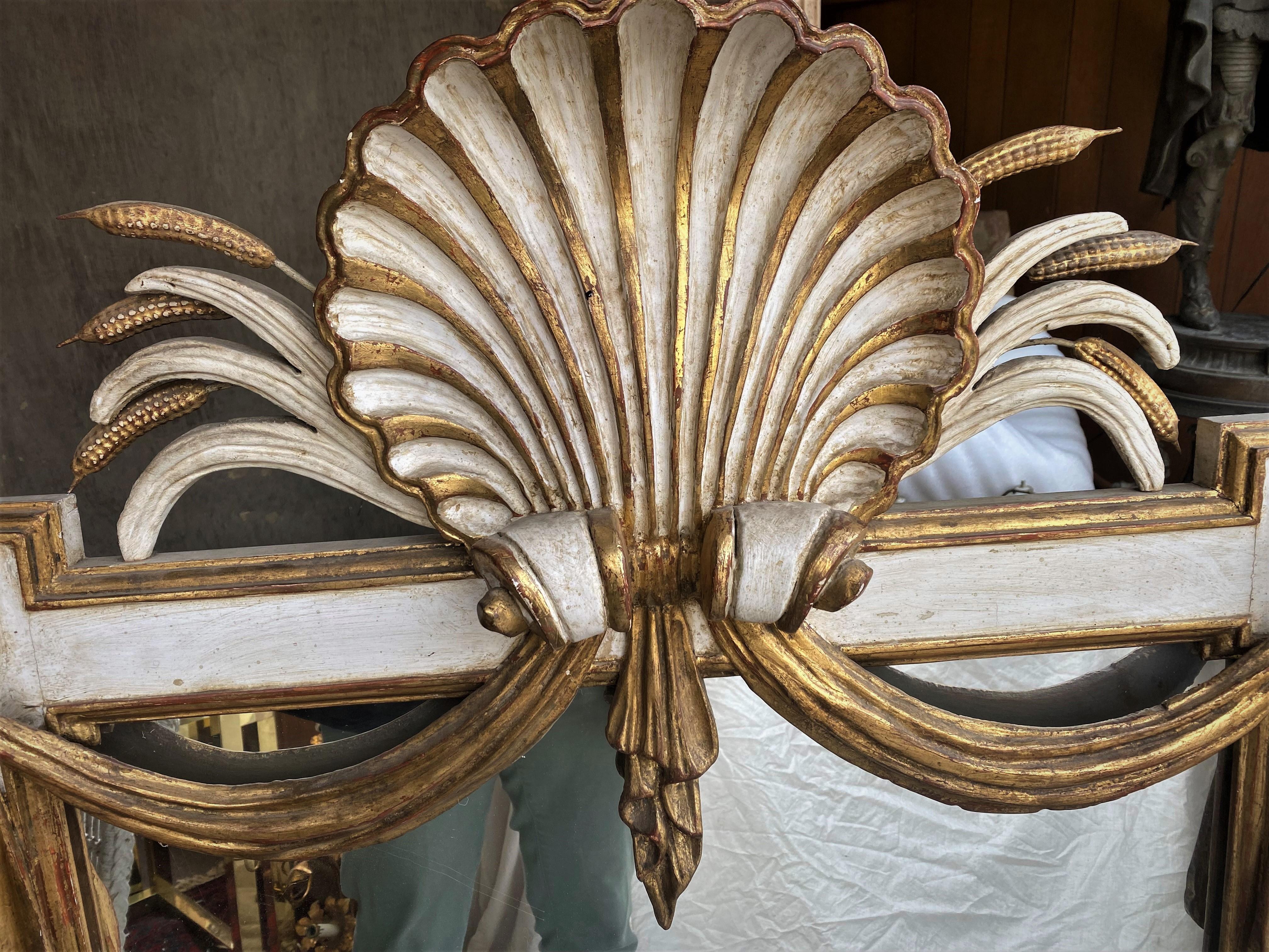 This is a fabulous Italian deeply carved large wood mirror with a prominent carved shell on the top center with sheaves of wheat spraying out to the sides and fabric gathered under the shell and draped in swags to the stars in the top two corners of