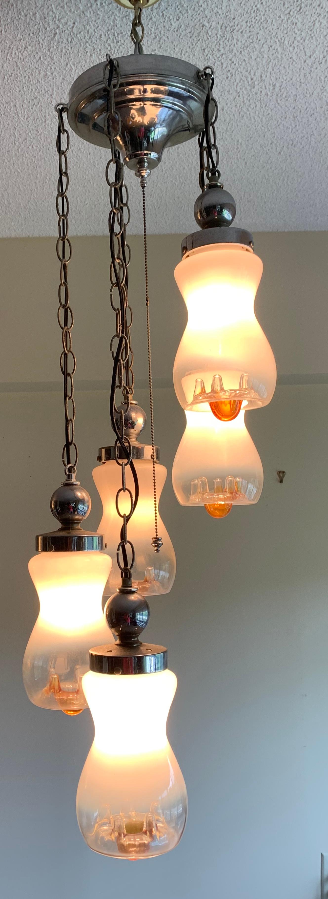 Cascading graduated midcentury Italian light fixture with 5 hand blown glass globes. Globes have amber drippings. 3-way switch lights one, two or all 5 pendants. Chrome holders and canopy. Opaline and amber creates enhancing accents adding tranquil