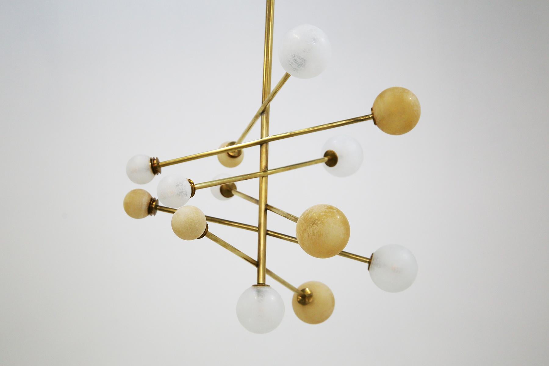 Imagine being enveloped in the enchanting light of an elegant chandelier, the Lunare model, a jewel of Italian design created in 2018. This chandelier features a tubular brass frame, its splendor shining not only because of its fine material, but