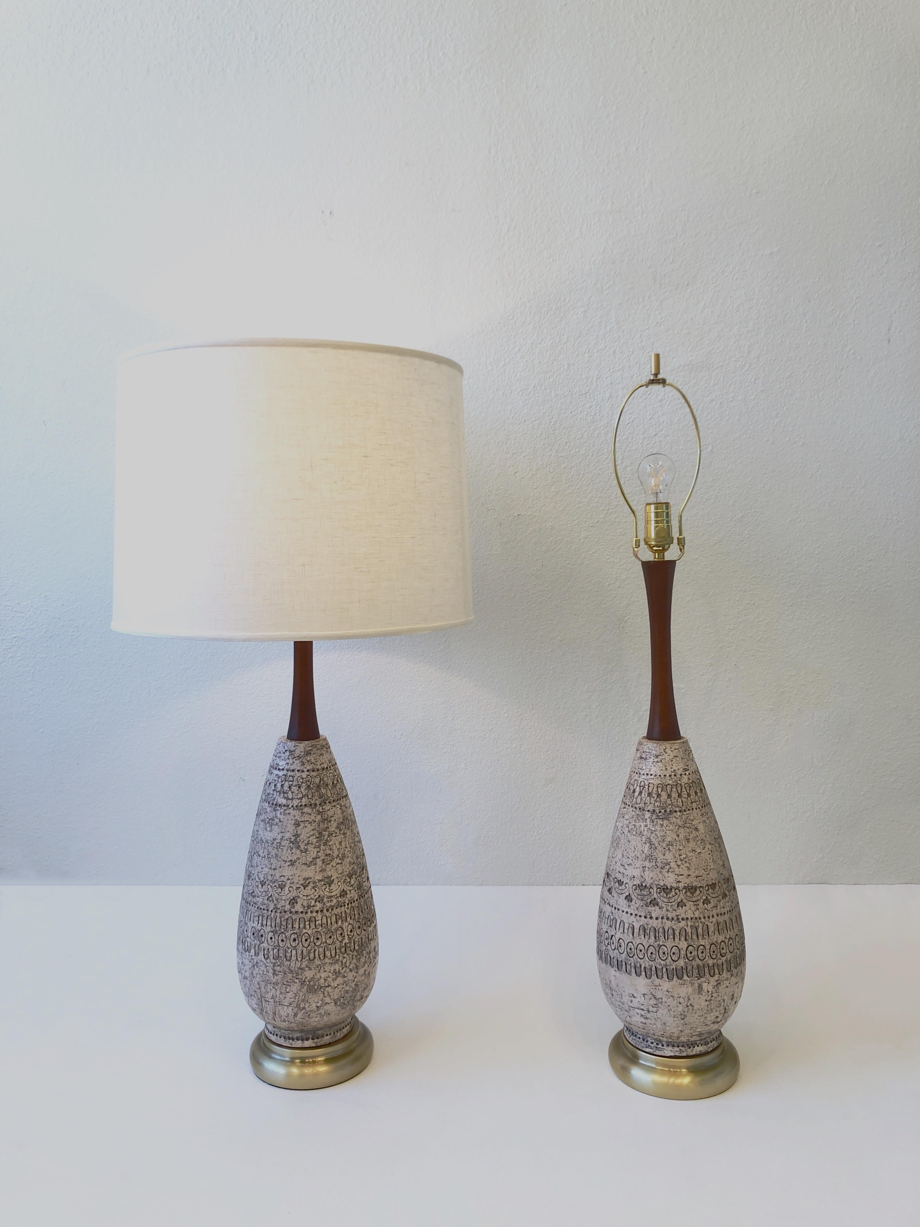 Pair of Italian ceramic and brass table lamps by Bitossi.
Constructed of glazed ceramic, satin brass base, walnut wood and linen. 
It takes one regular Edison lightbulb 100w max. Dimmer can be added if desired. 
Newly rewired with new polish