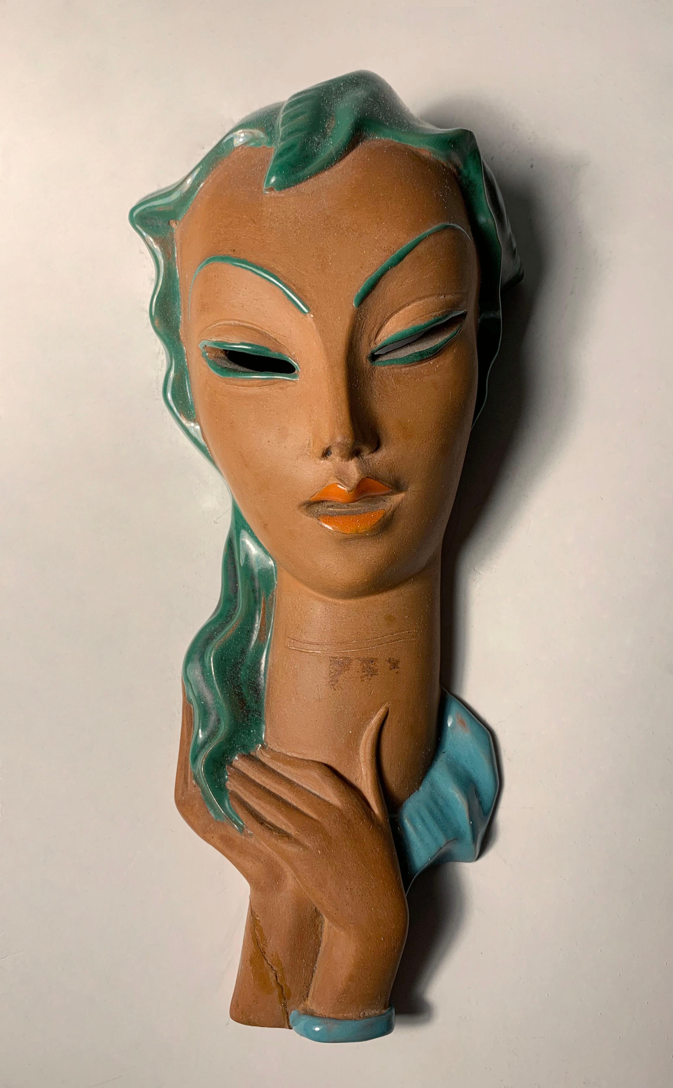 An Italian ceramic Art Deco hanging wall mask bust of a woman. Similar to the works of Goldsheider. This mask is marked Italy on backside along with what seems be a makers mark and model number.

At some point in time someone repaired the piece in