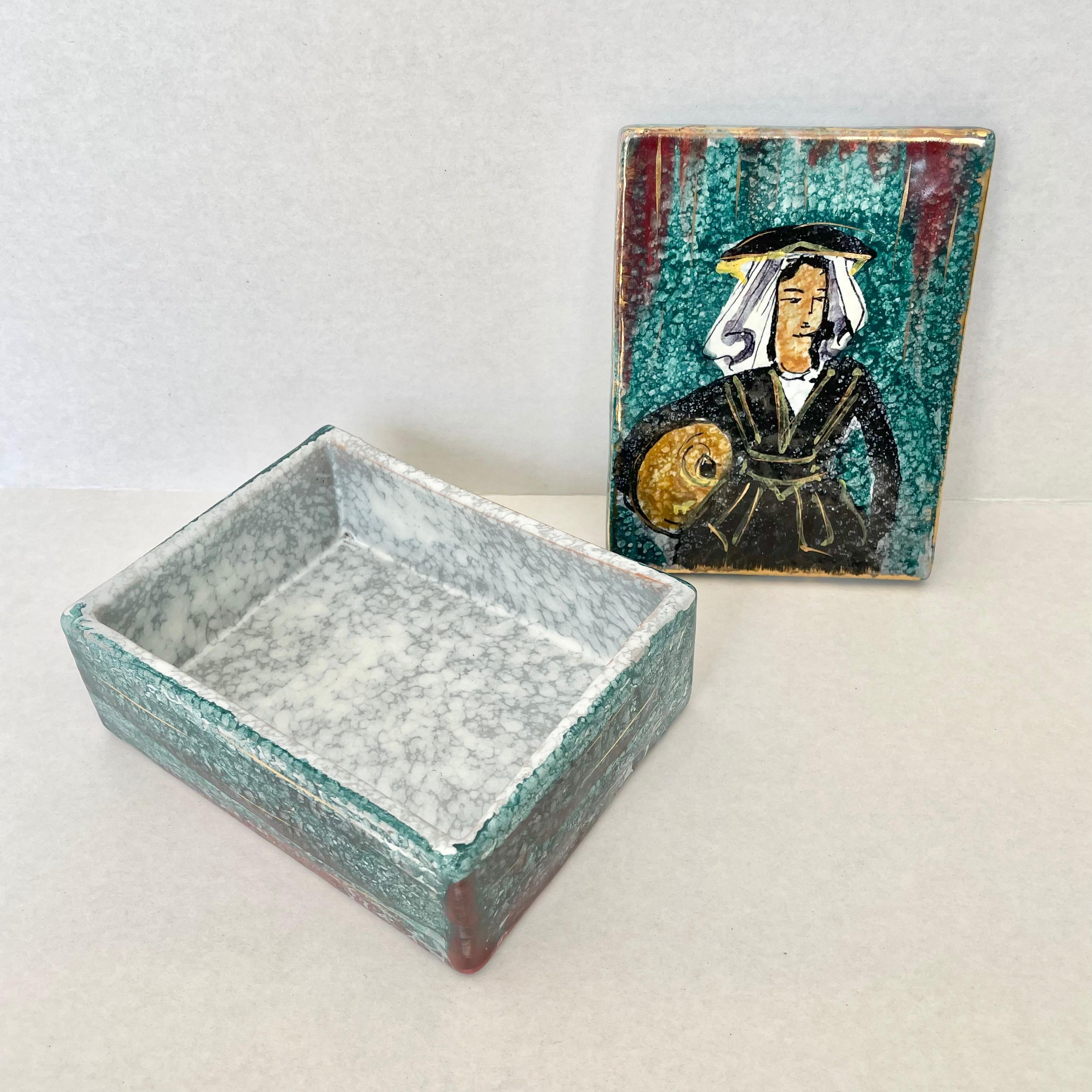 Artistic glazed ceramic box made in Italy, circa 1970s. Beautiful painting of woman in a black robe and hat with a white sun cover. Accent hues of maroon, gold and green throughout. Great vintage condition. Fun stash box and tabletop object. Marked