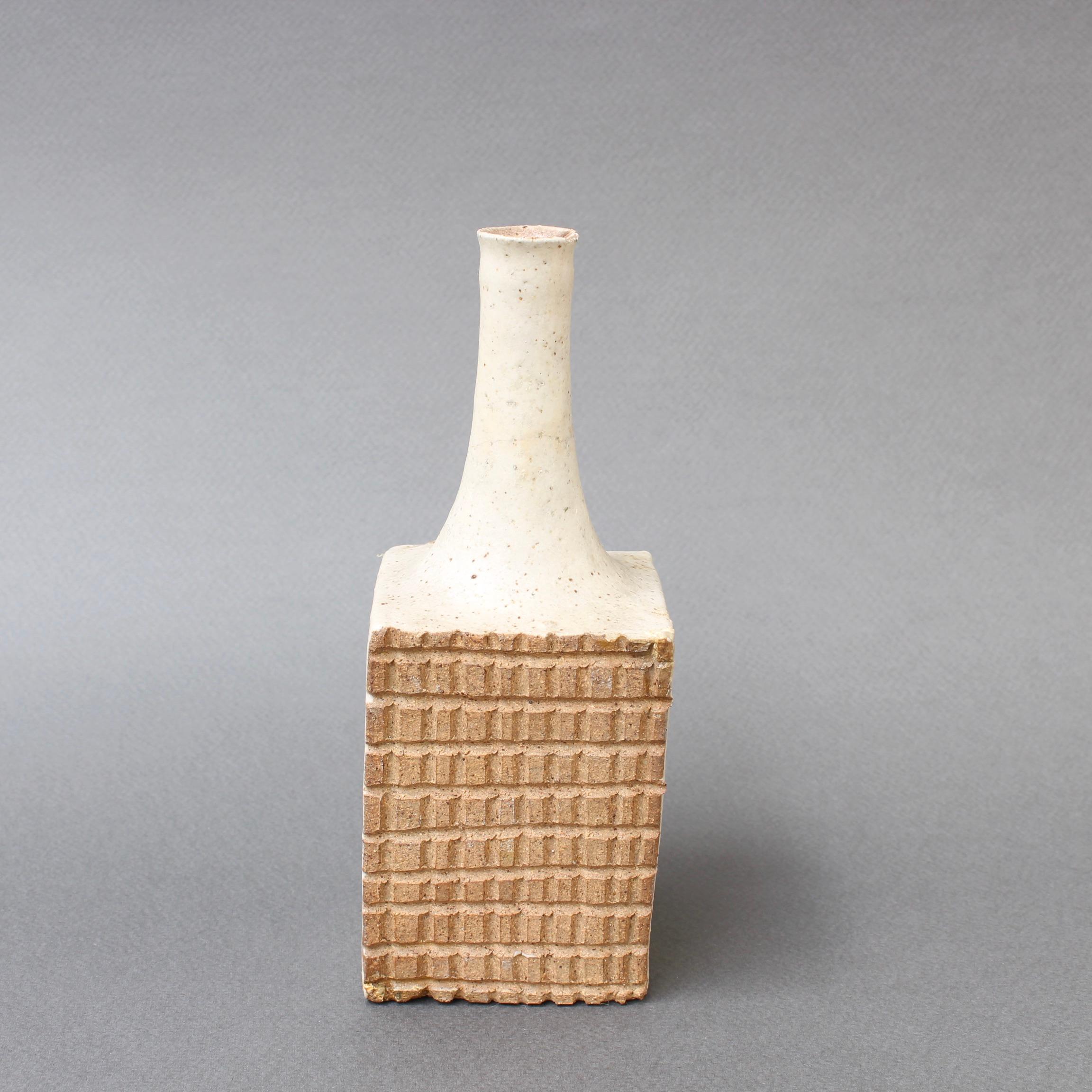 Italian ceramic decorative bottle by Bruno Gambone (circa 1980s). A graceful, diminutive piece with a rectangular base is capped by a long, elegant mouth. Two sides of the bottle are graced with lines of smaller, sandy-colored repeating rectangles
