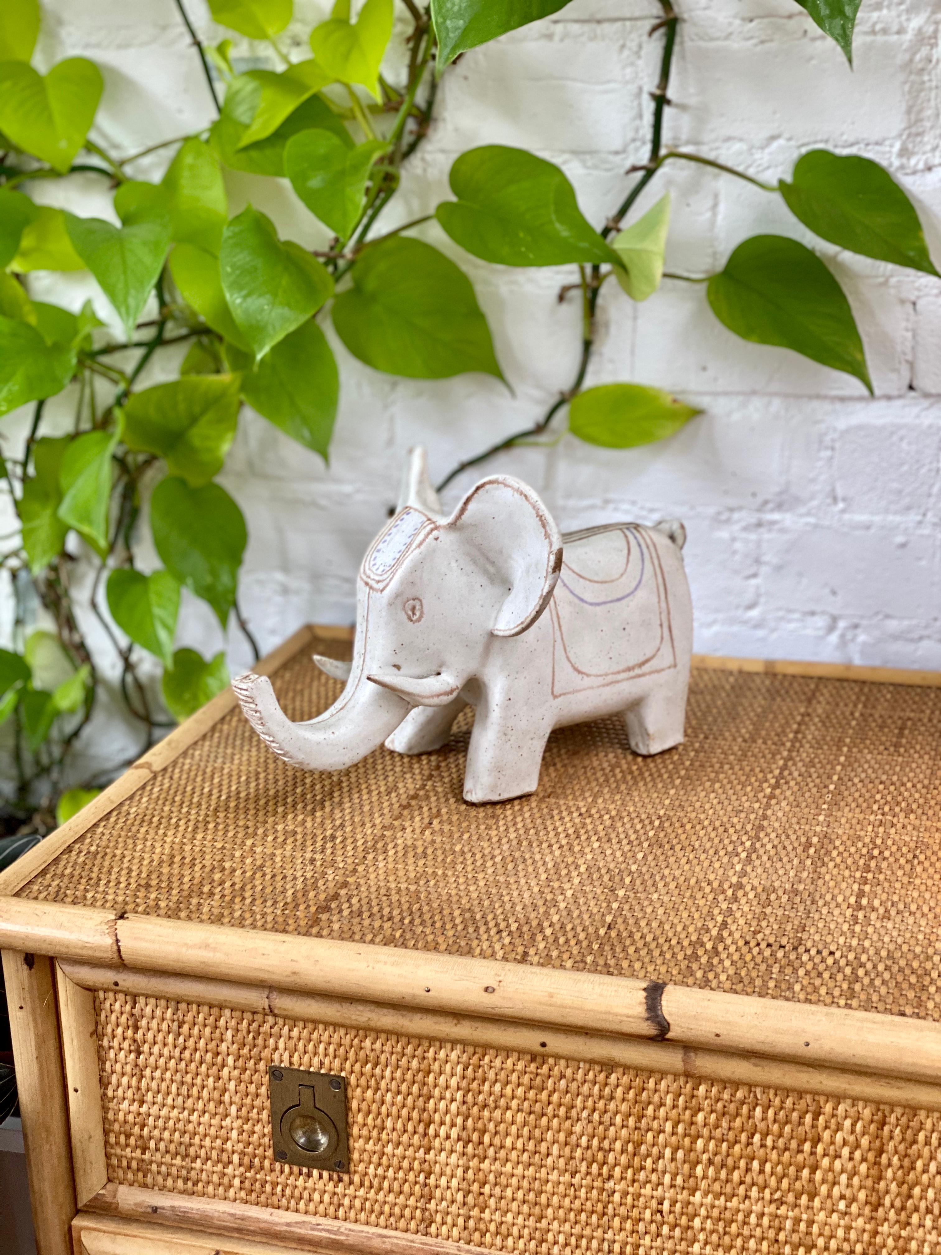 Ceramic Indian motif white elephant by Bruno Gambone (circa 1970s). This is an absolutely charming ceramic white elephant with an Indian-style blanket and headdress, large whimsical ears and tusks in Gambone's signature chalk-white. Light brown and