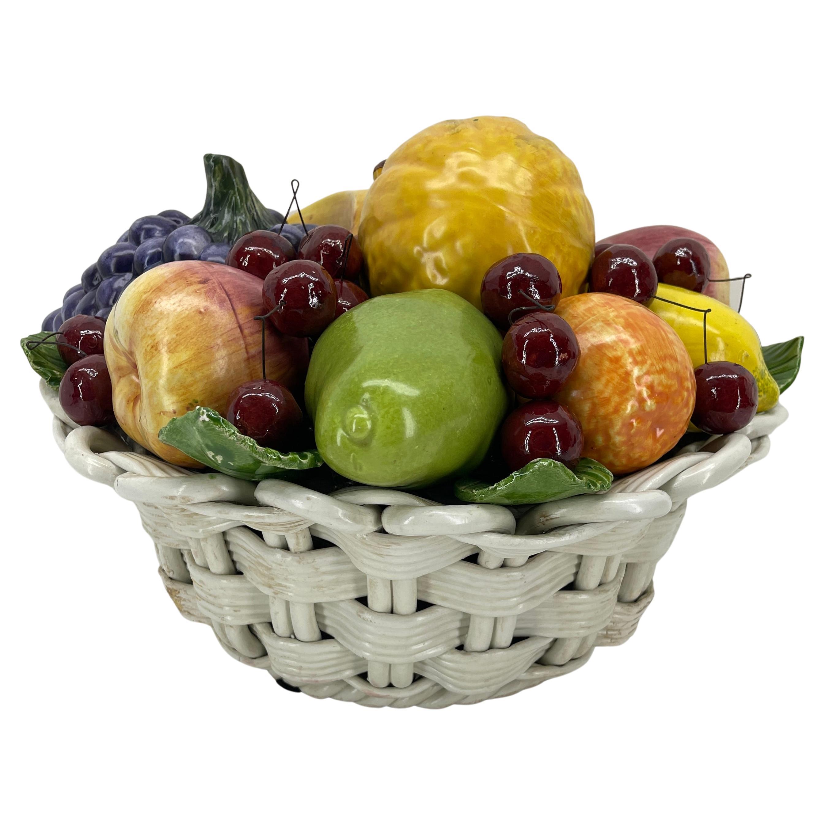 Italian glazed ceramic fruit basket figure sculpture. This polychrome compote is handmade with the greatest attention to detail, to a degree that the fruits are basically unrecognizable from real fruits. 
The basket is marked Made in Italy on the