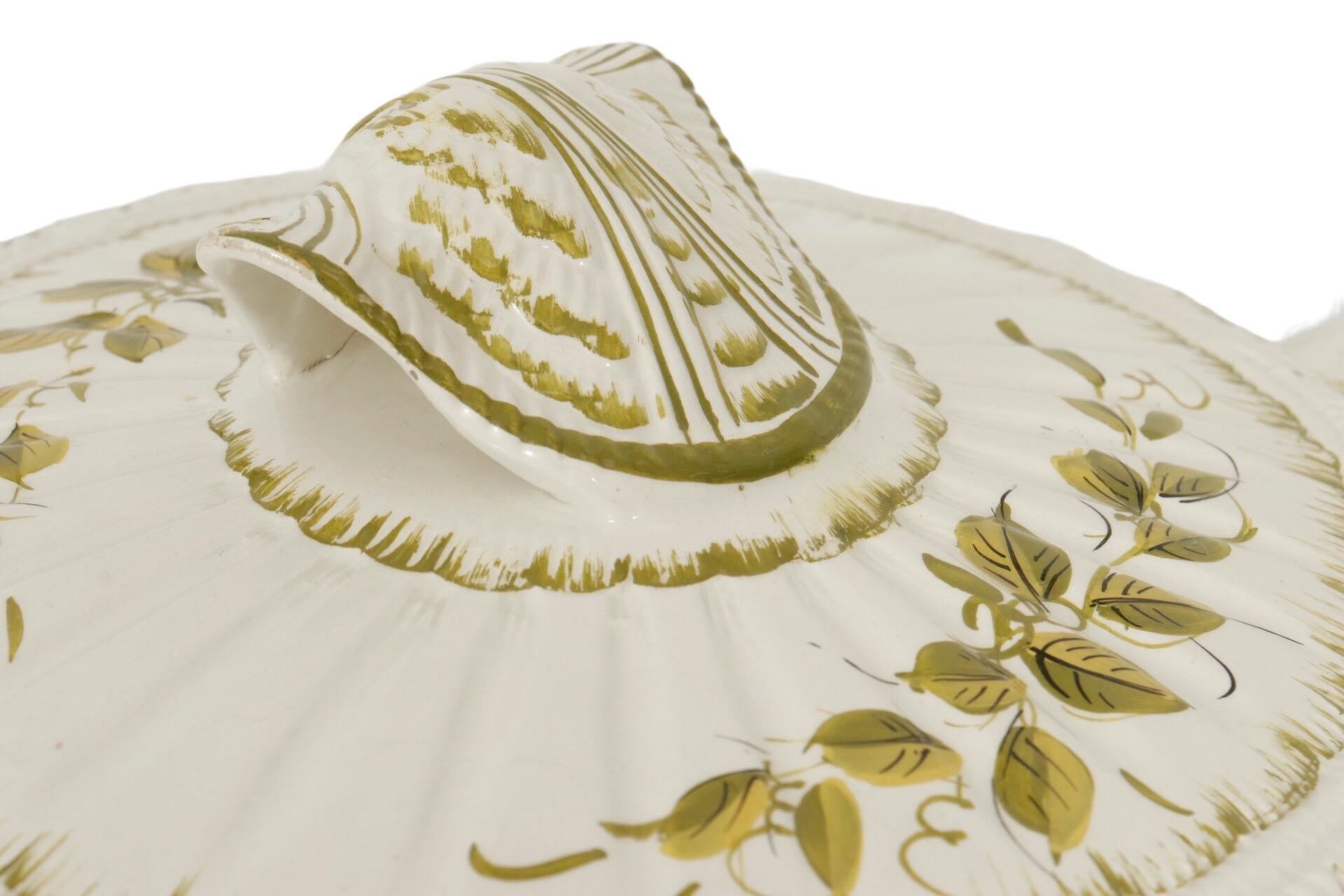 A large Italian hand painted ceramic soup tureen. The lid, ladle, tureen and charger are white and delicately decorated with hand painted green vine leaves and scallop shells. Marked underneath with a hand signed limited edition number “46/7” and