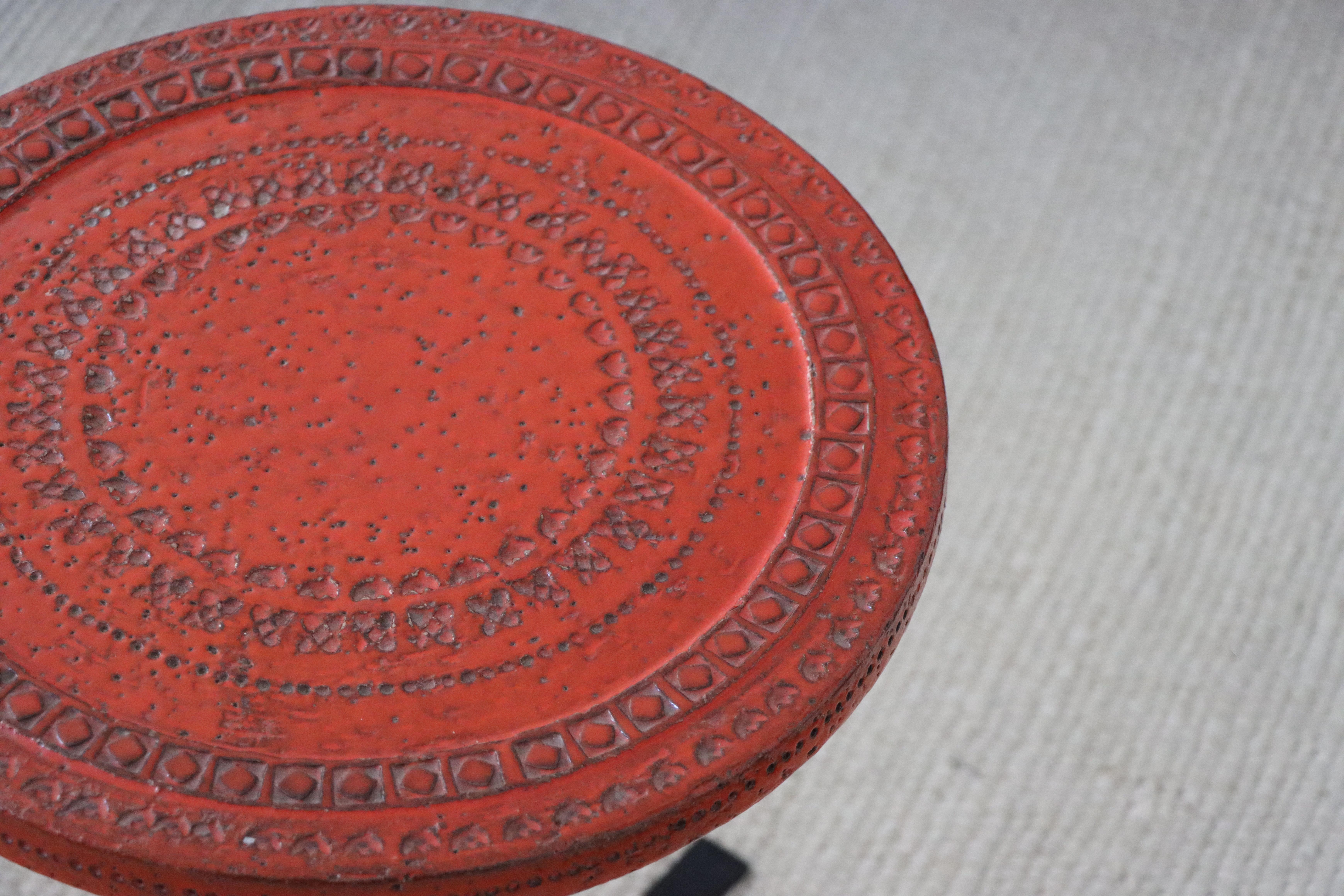 Small Italian side table designed by Aldo Londi for Bitossi in an uncommon color. This example features a lovely orange/red glaze on top of a tapered teak stem and cast iron base. The top is hand glazed and decorated in Italy while the stem and base