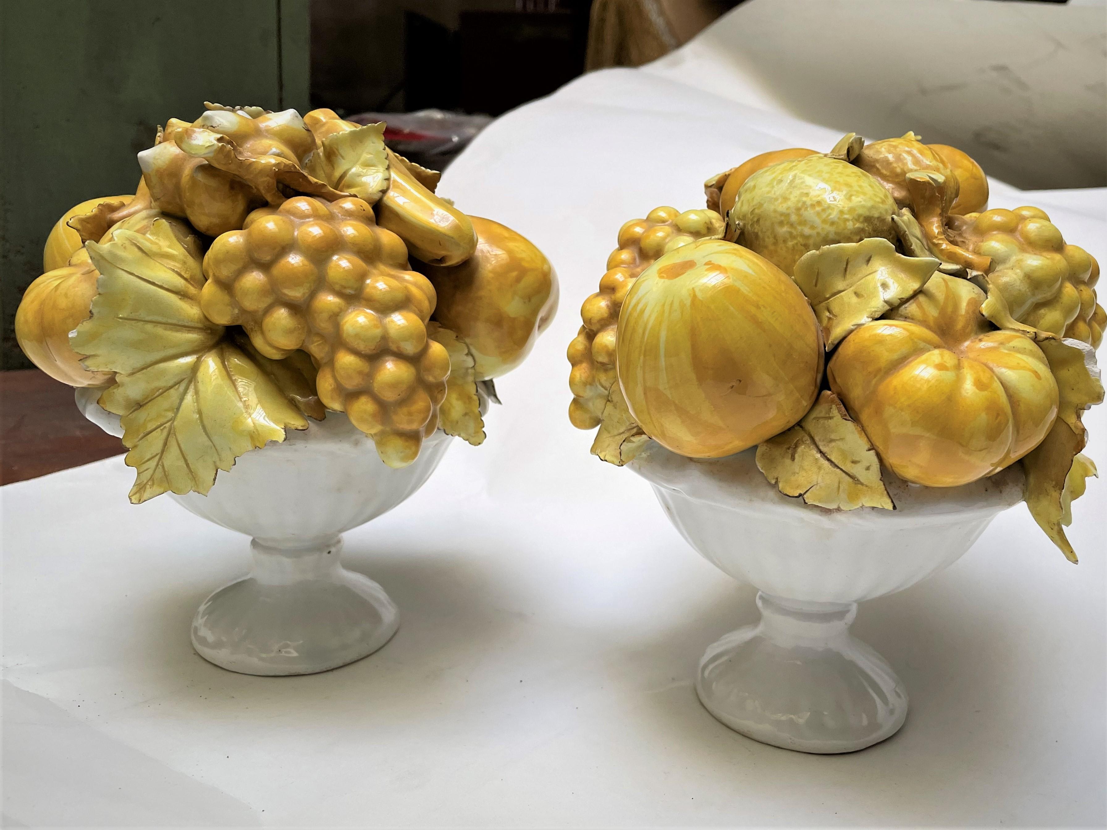 This is such a wonderfully designed pair of Italian ceramic white footed bowls full of realistic fruit that have been finished in a yellow glaze, making a bright and festive pair of centerpieces or decorative accessories. The neutral white and