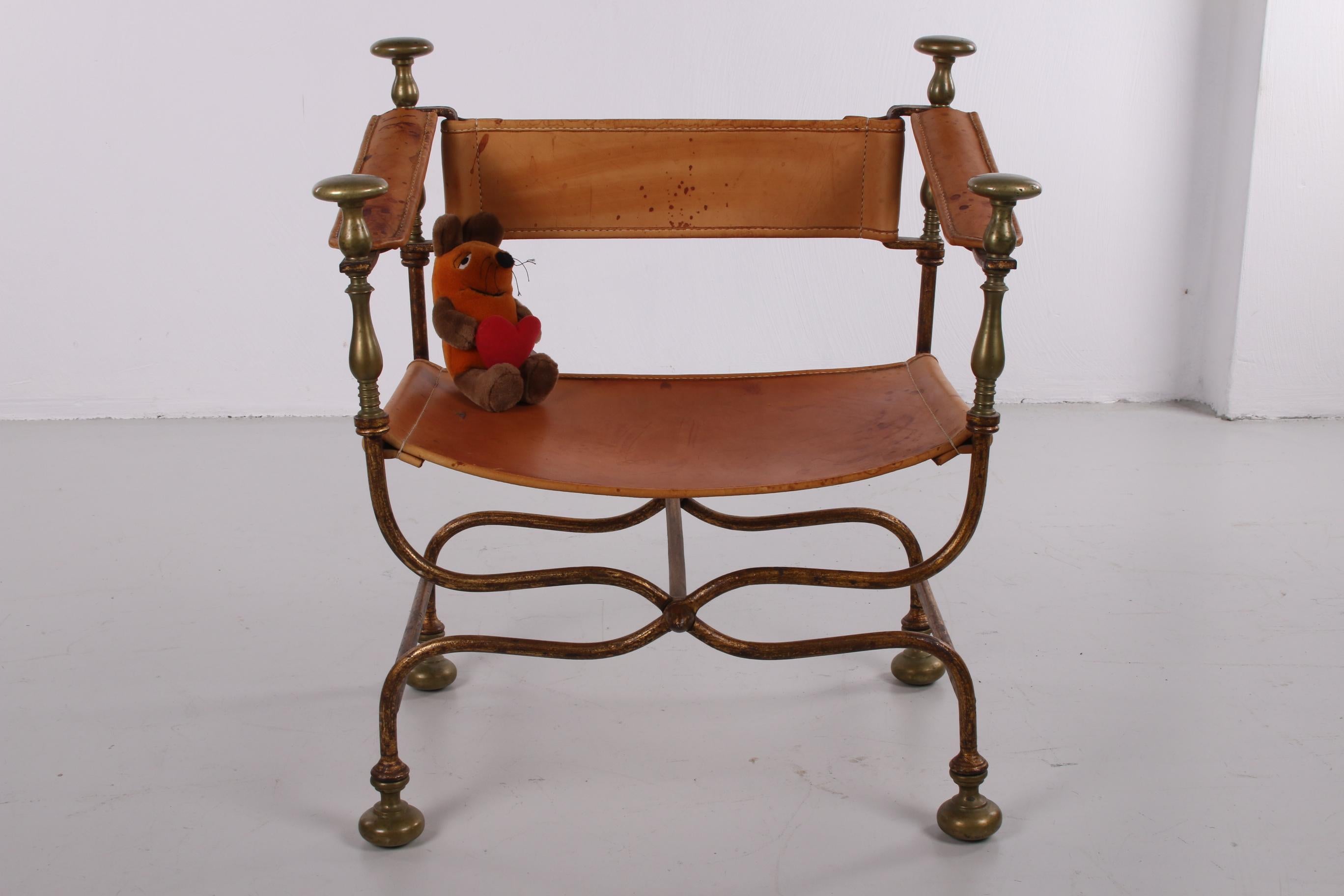 Beautiful chair Italian Savonarola Dante chair. 
Features a bronze scissor-style frame that folds into Campaign style with brass-mounted end pieces and feet. 
The seat, back and arms are covered with thick, weathered leather hides with a