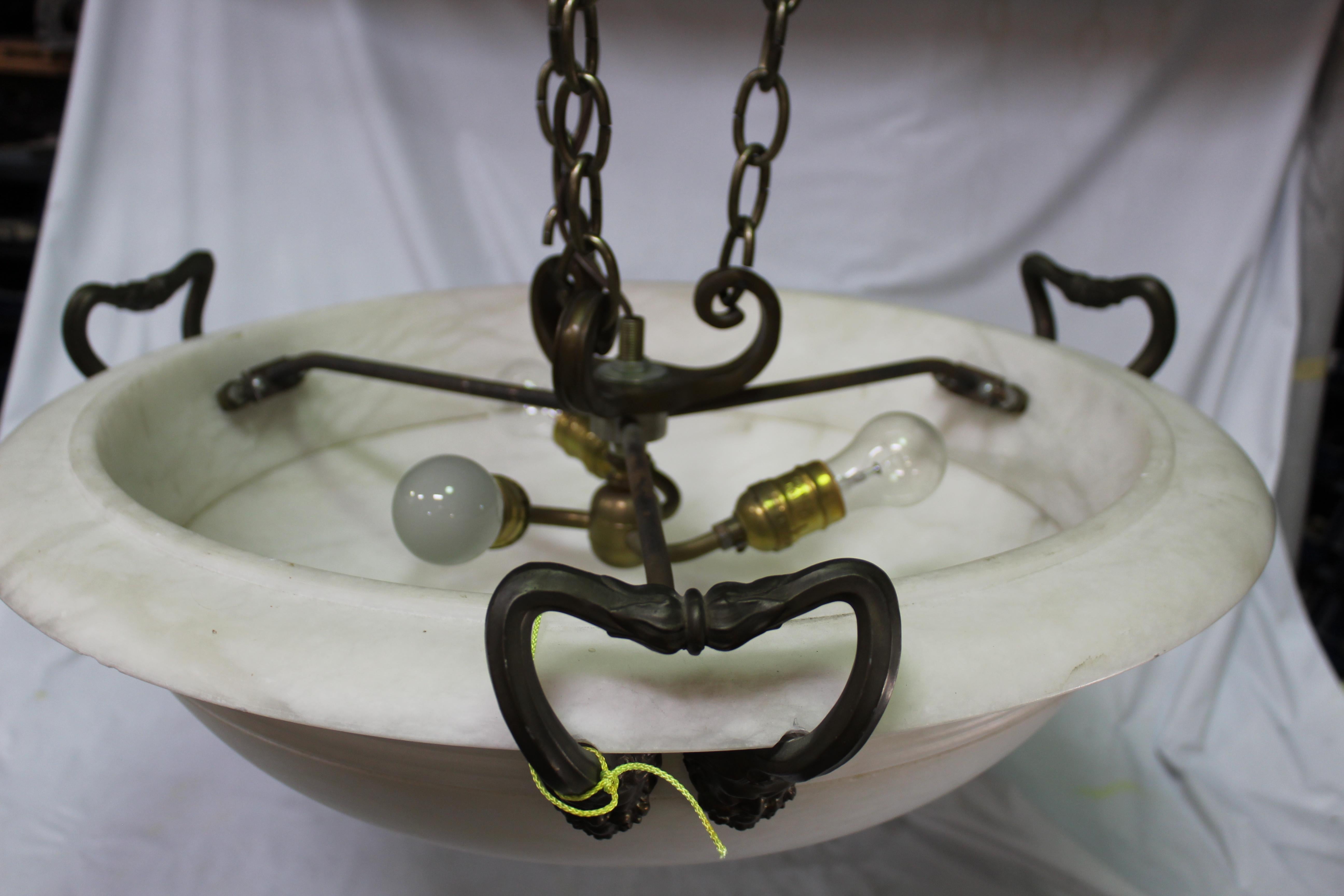 European design Alabaster chandelier with bronze man's face appliques. With 3 handles supported by chains and a bronze cast ceiling cap. Has e light sockets. Appox 24 