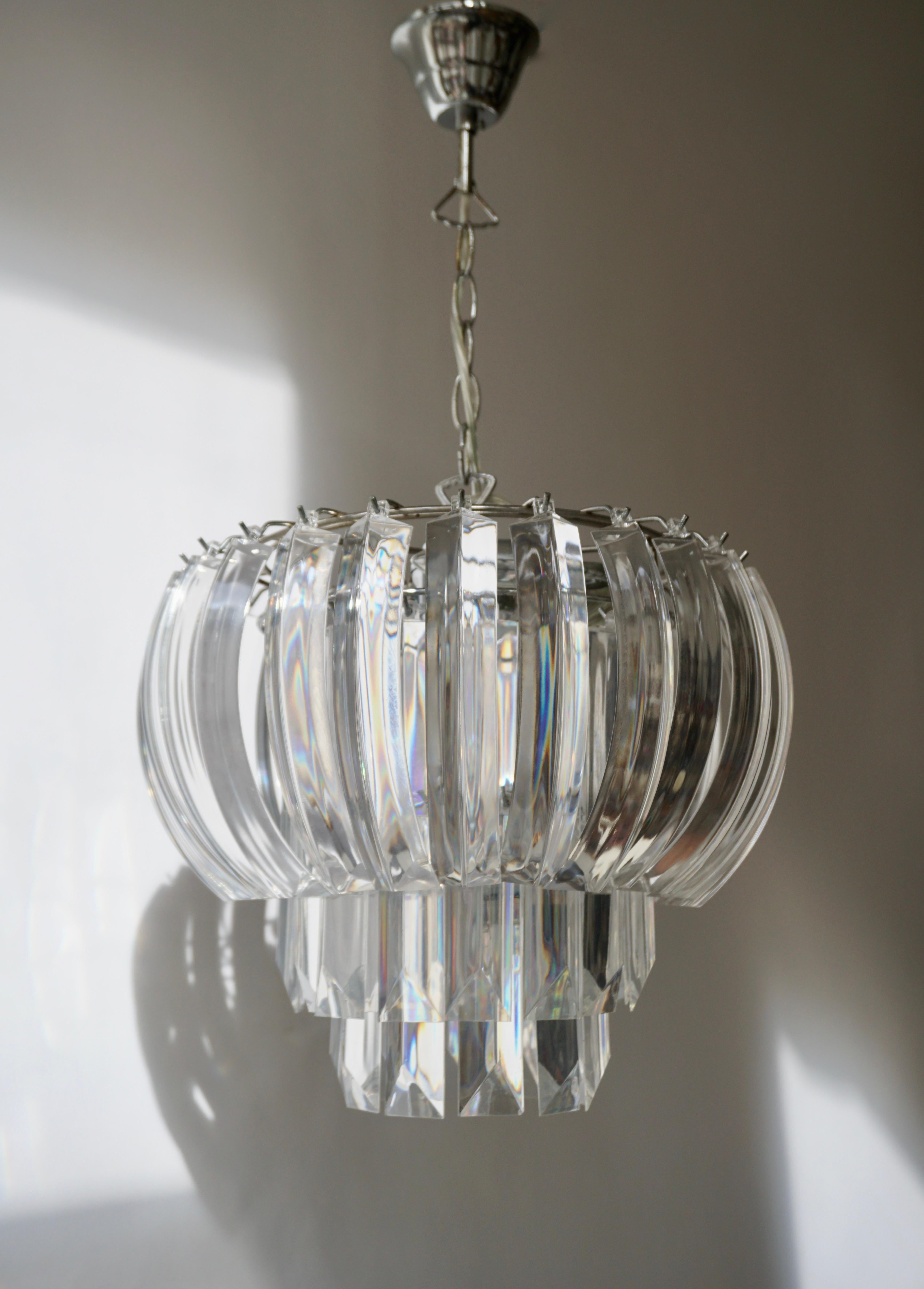 A waterfall chandelier comprised of prismatic plastic sections with angled ends.

Measures: Diameter 38 cm.
Height fixture 30 cm.
Total height including the chain and canopy 80 cm.
The light requires three single E14 screw fit light bulbs