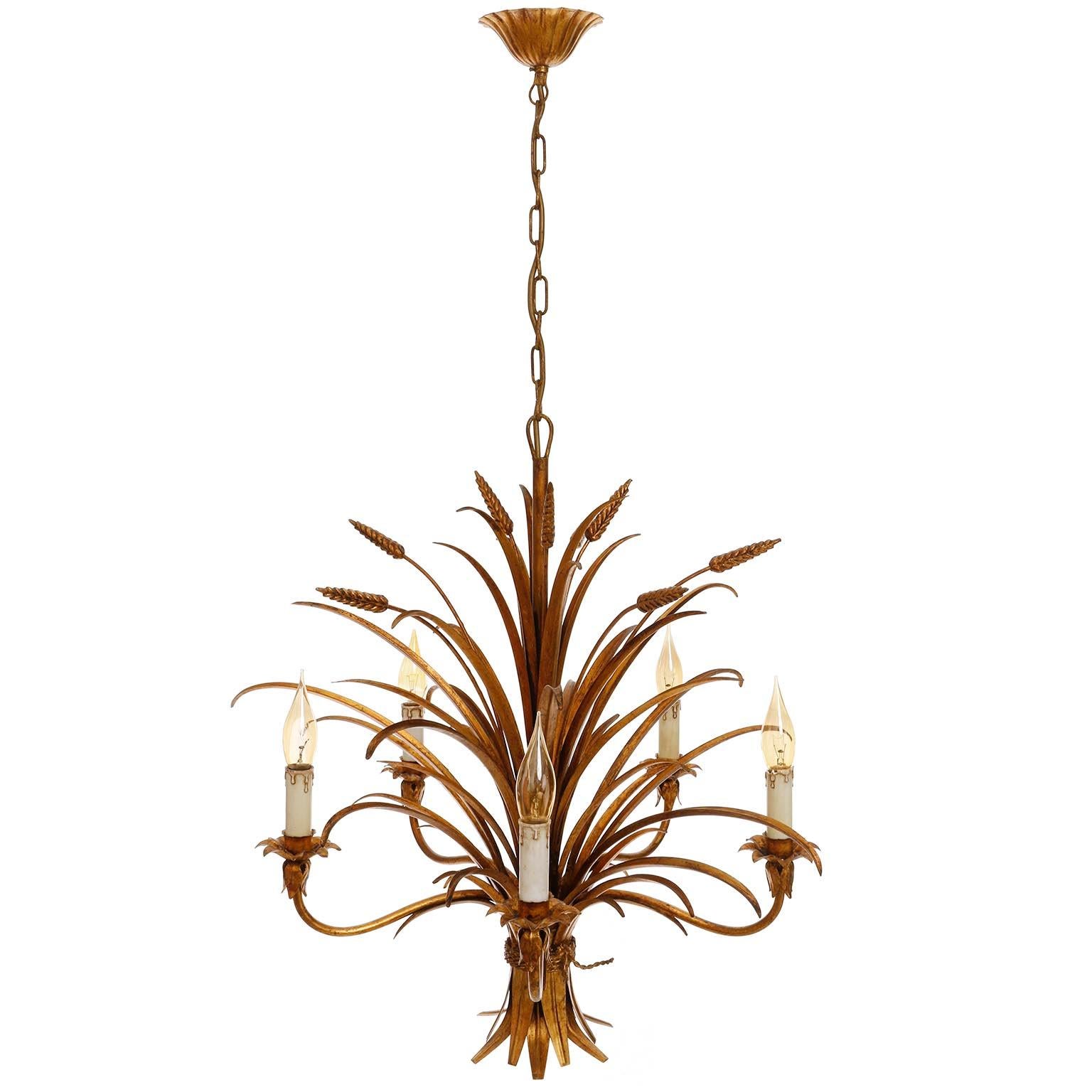 A Hollywood Regency five-arm light fixture from Italy manufactured in midcentury, circa 1970 (late 1960s or early 1970s). 
It is in the form of a bunch of wheat sheafs and it is made of antique leaf gold plated metal. 
The lamp has five sockets for