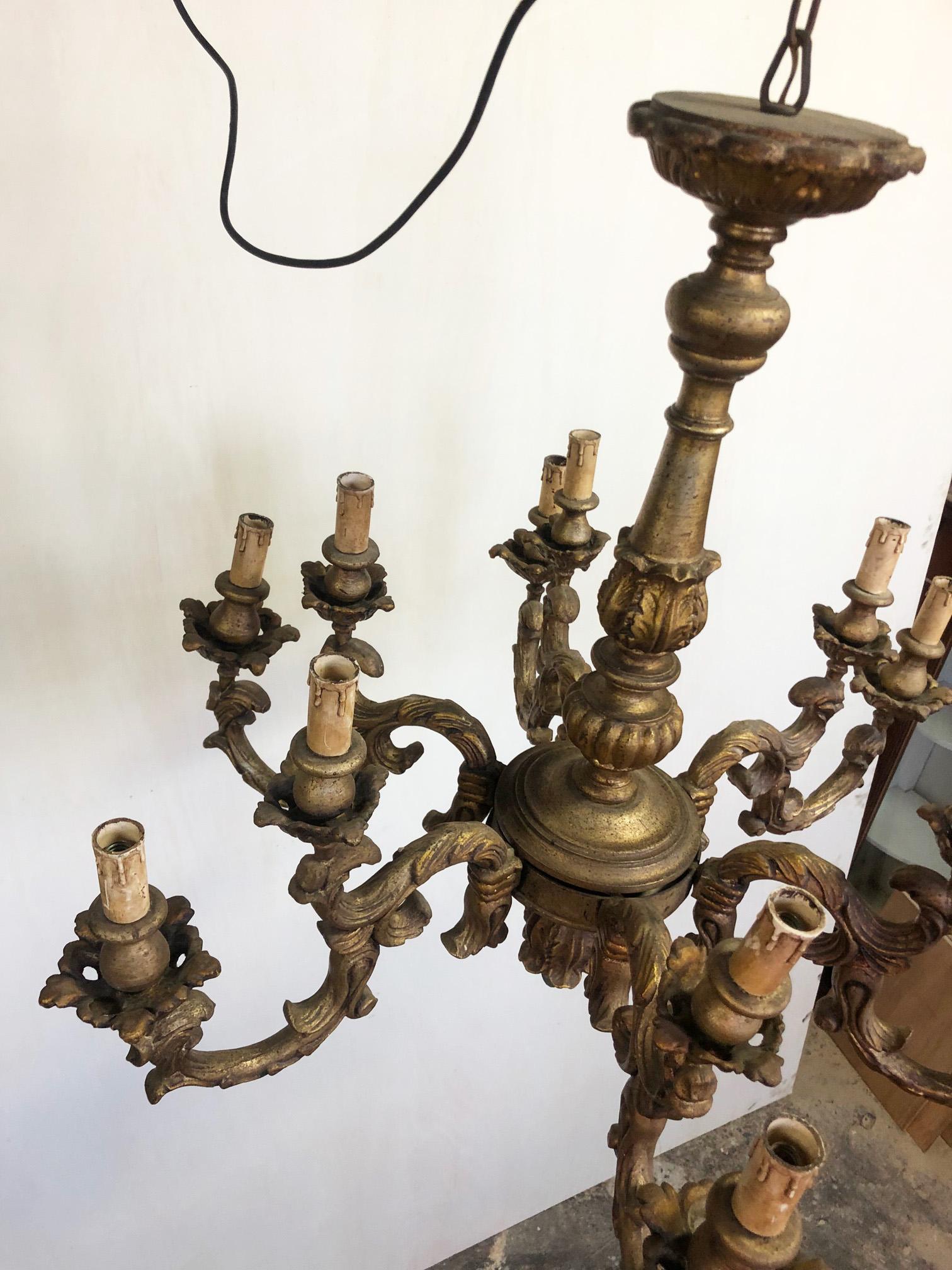 Italian chandelier with 12 lights, gold wood, very elegant.
Original from 1970. 
Very special patinated color.
Comes from an old city villa in the Florence area of Tuscany.
As shown in the photographs and videos, there are some small imperfect