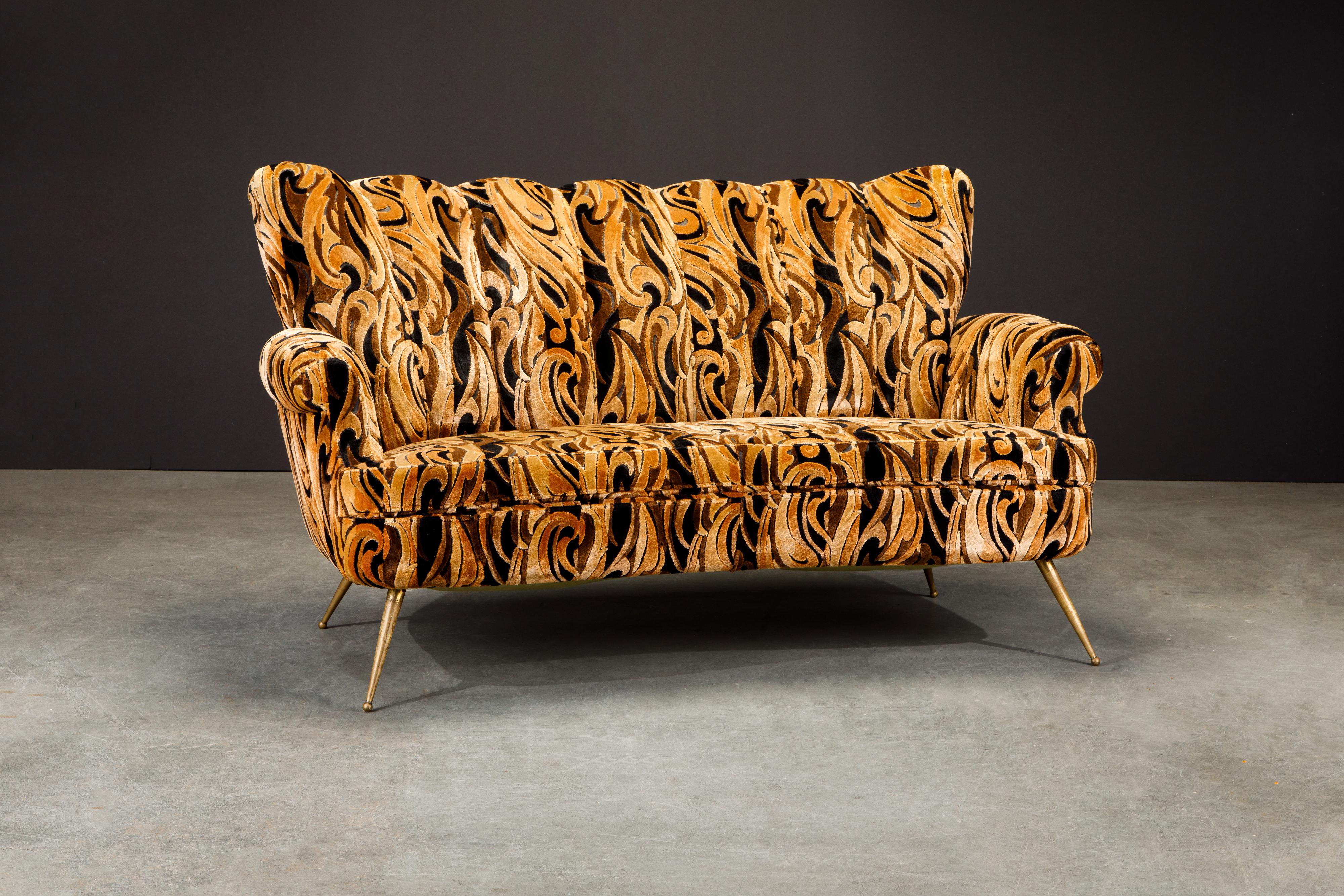 This gorgeous Italian Mid-Century Modern loveseat features a channel tufted fluted cushioned back over a curve shaped seat in brown and black cut velvet upholstery rising on tapered brass legs. Such groovy fabric, get this for your interior design