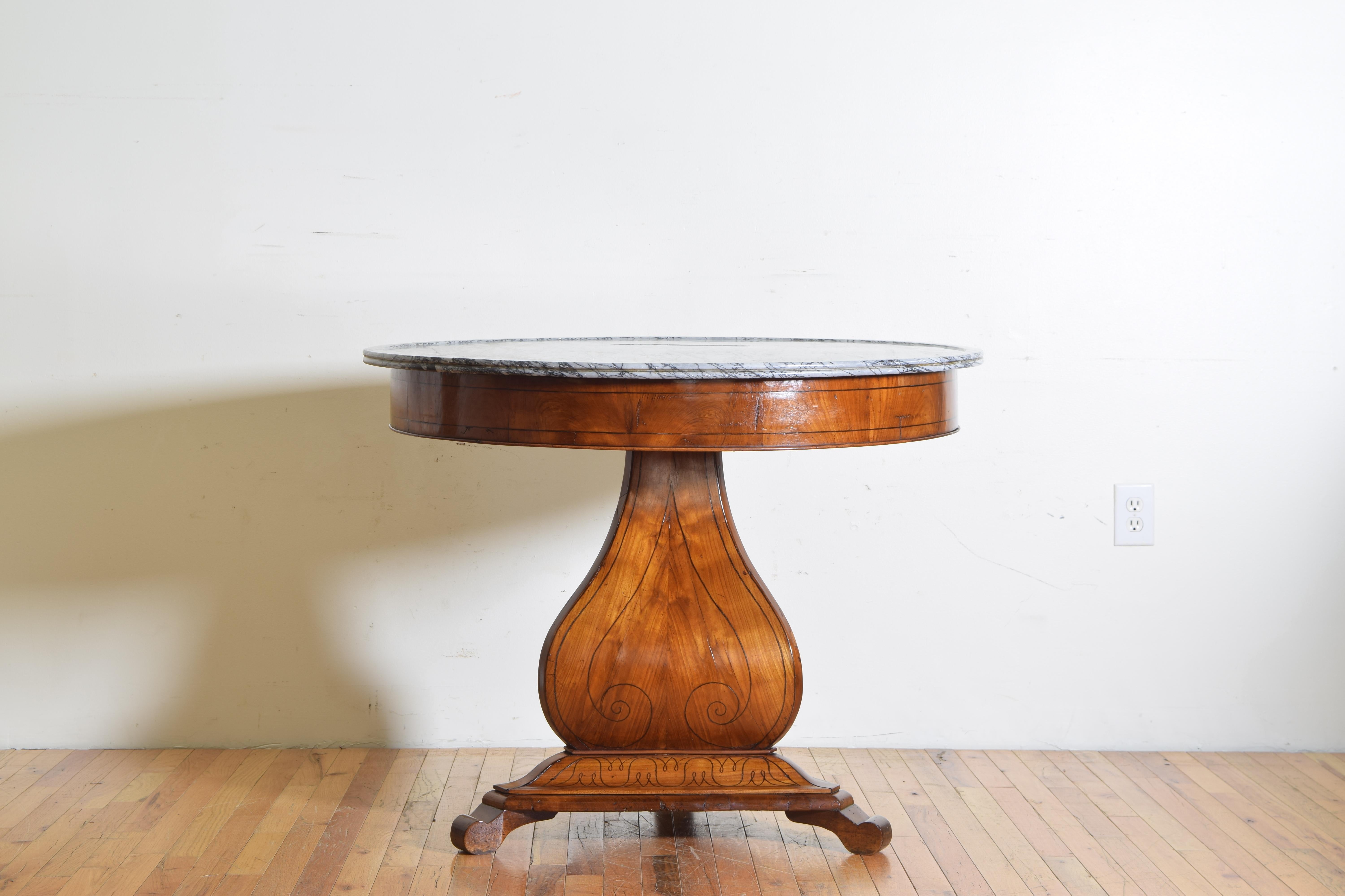 Having a circular marble top with a raised and molded edge resting atop an apron with horizontal ebonized band inlay, the spade shaped standar with similar ebonized band inlay atop a tripartite base with florial inlays and issuing three scrolling