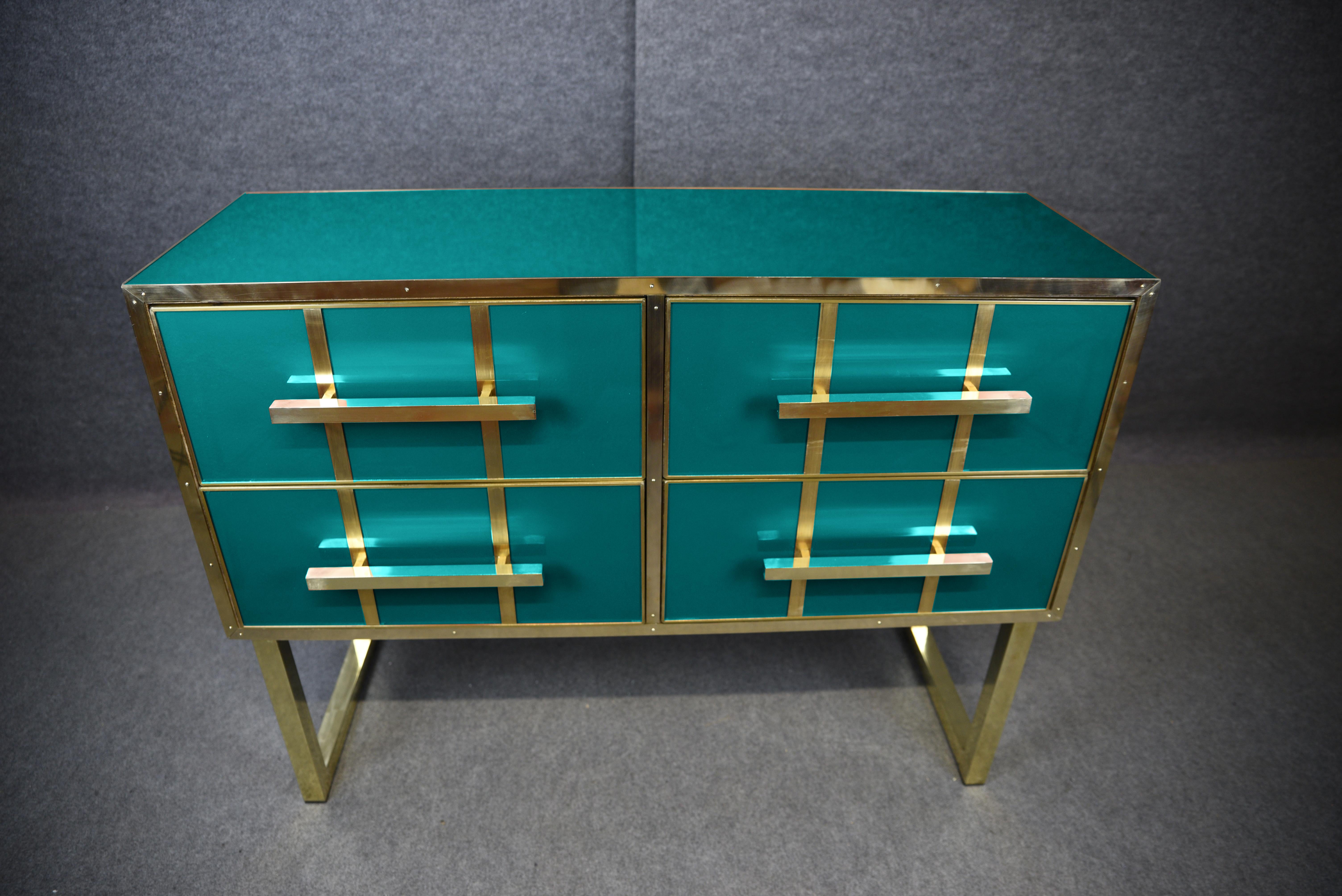 This stunning Italian chest of drawers embodies the essence of mid-century modern style with its exquisite blend of solid wood, aqua blue Murano glass and polished brass fittings. 

Hand-painted and crafted with meticulous attention to detail, it
