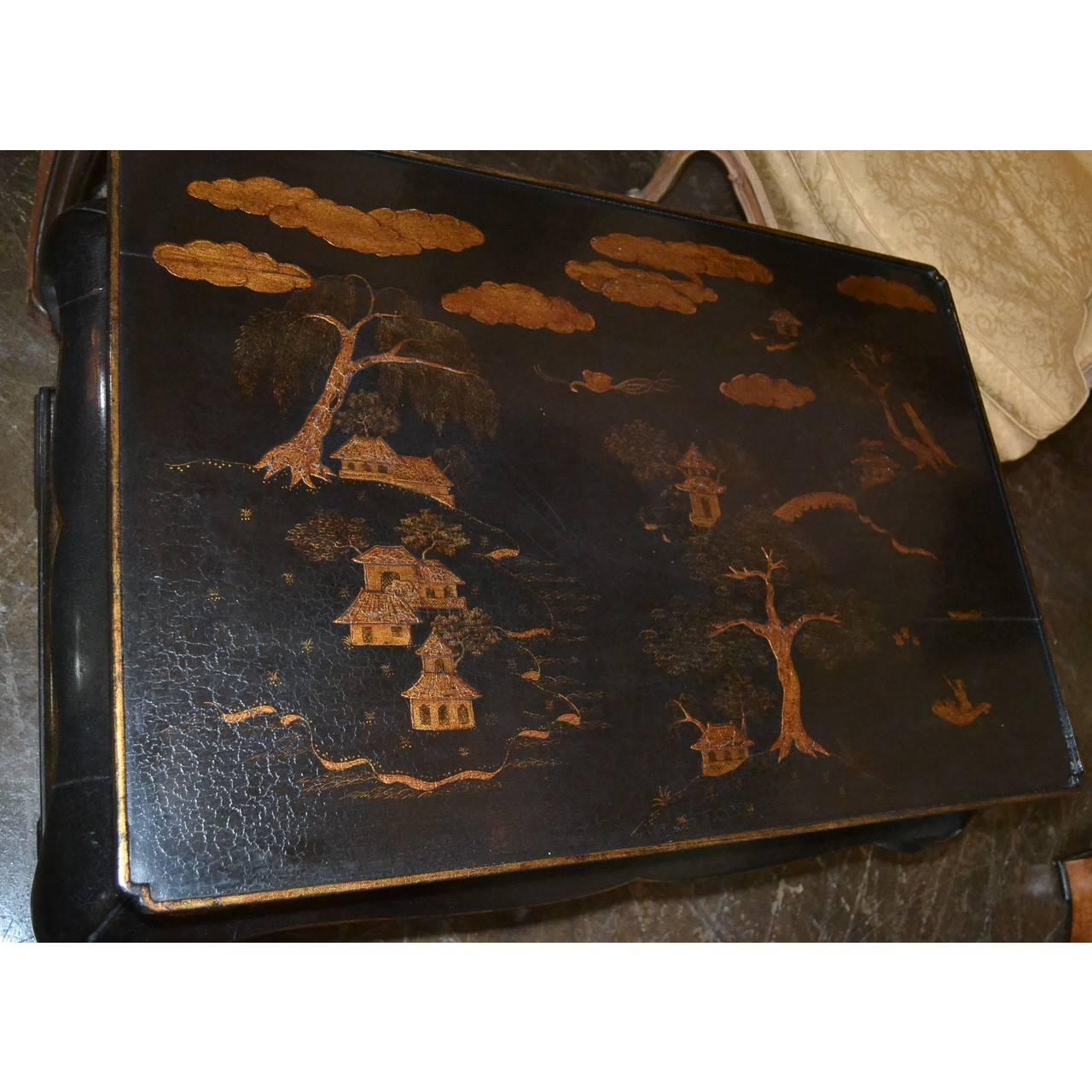 Exceptional Italian black and gold lacquered coffee or cocktail table on cabriole legs and lower tier, circa 1910. The Chinese chinoiserie decorated top with a beautiful river and landscape scene with floating clouds above pagodas, large trees and