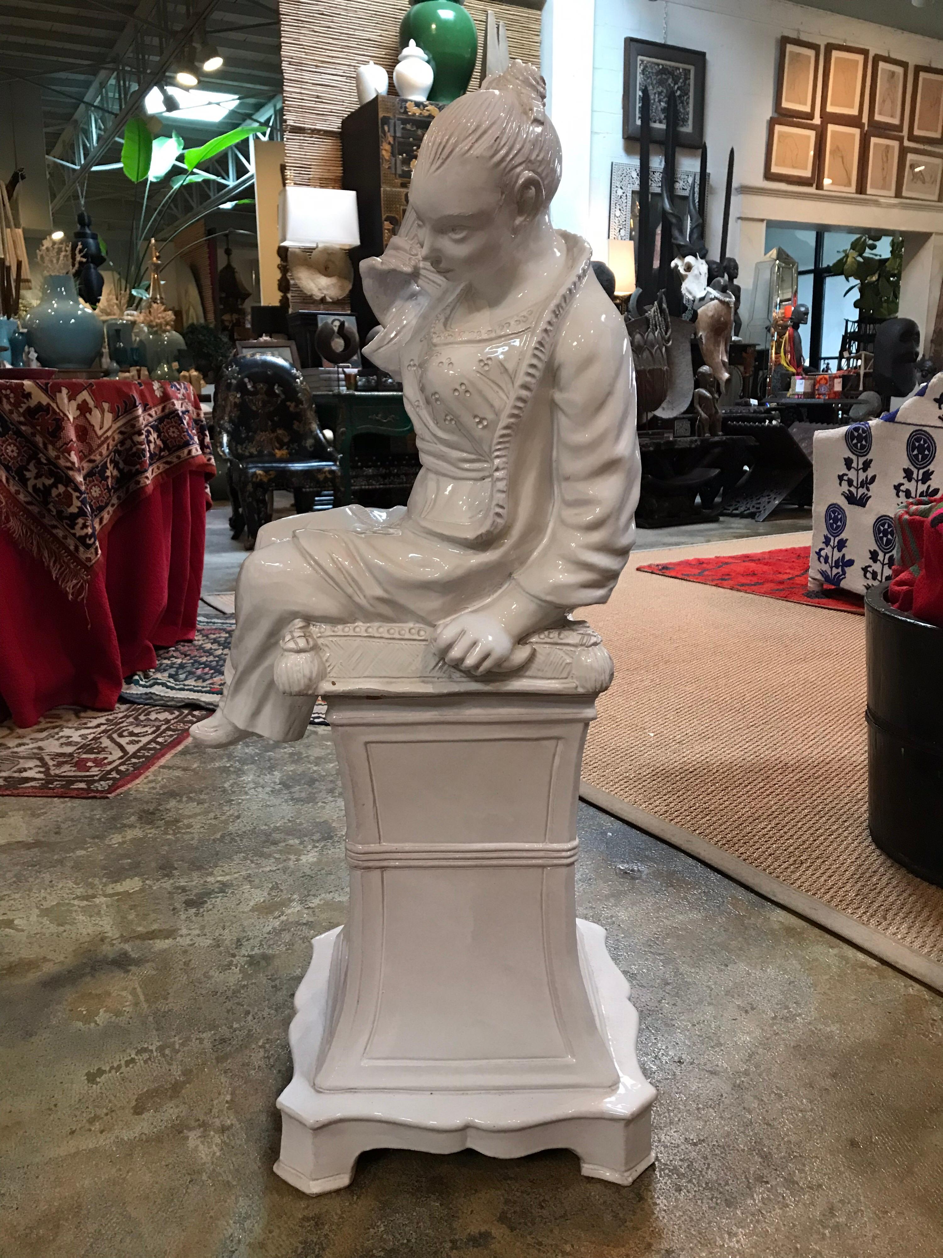 Midcentury 1970s Italian ceramic chinoiserie statue. This white ceramic chinoiserie statue is of a woman shyly fanning herself while looking down from her pedestal. The white luster of the ceramic surface grabs your attention, while the detail of