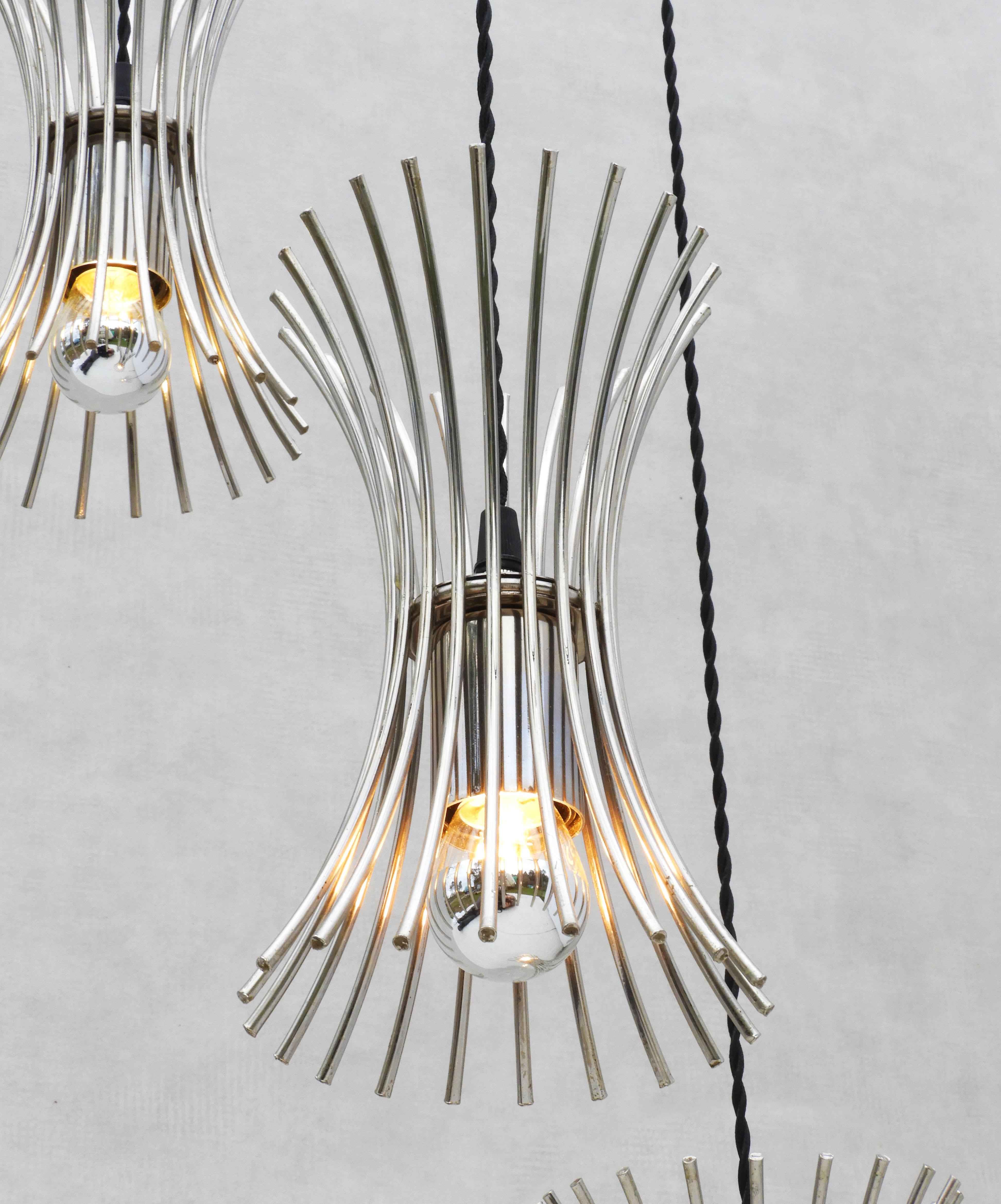 Unusual Italian three-light cascade chandelier C1970.
A trio of pronged cylindrical hourglass forms in chrome, suspended from a central three-armed ceiling rose.  The drop(s) on this striking light fitting can be adjusted to suit your requirements