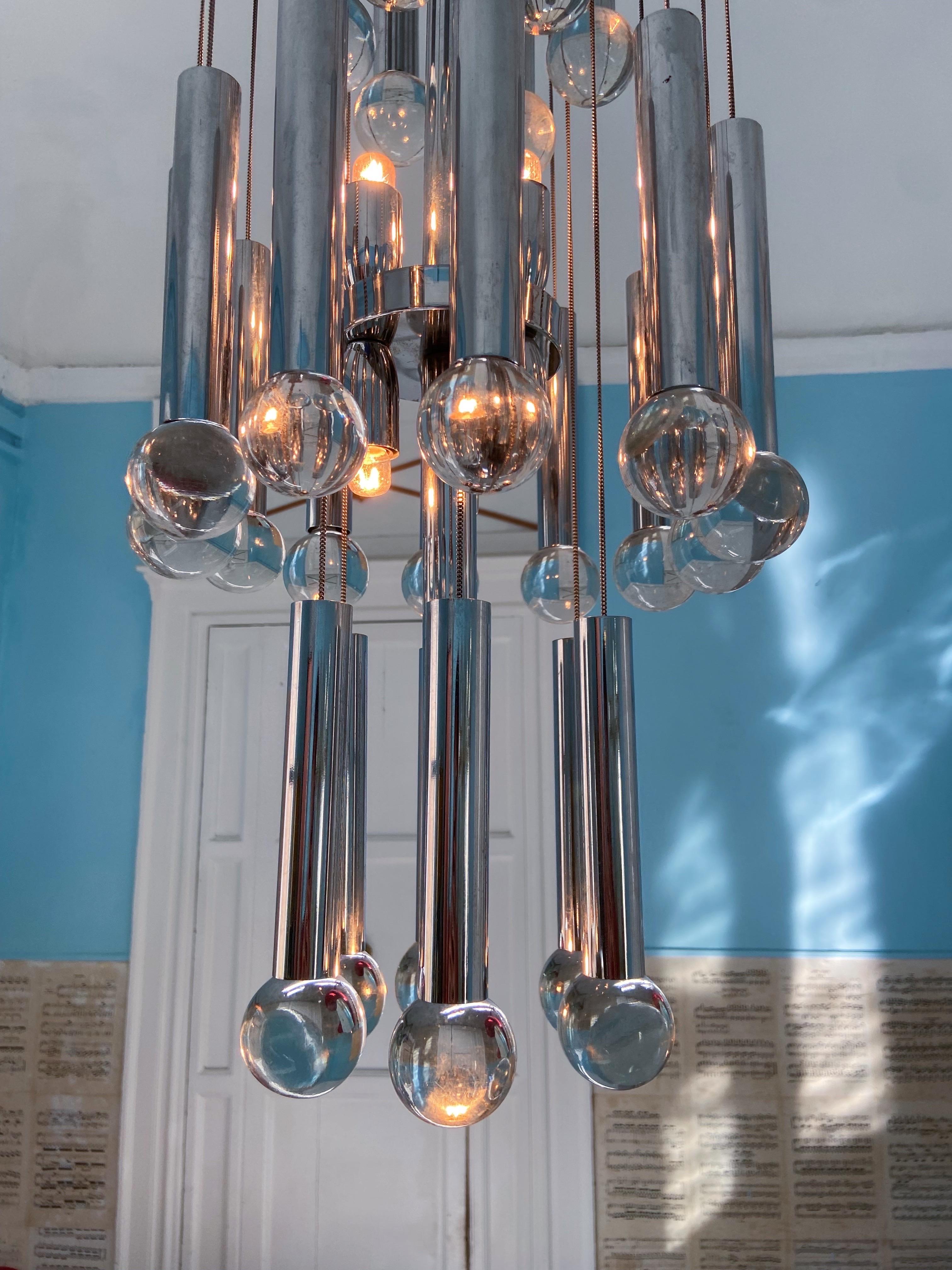 Beautiful 1970s chandelier by Gaetano Sciolari. The chromed structure supports 24 chains with chromed tubes and crystal balls. The light has seven light sources. In very good vintage condition with light wear on the metal.

Creator: Gaetano