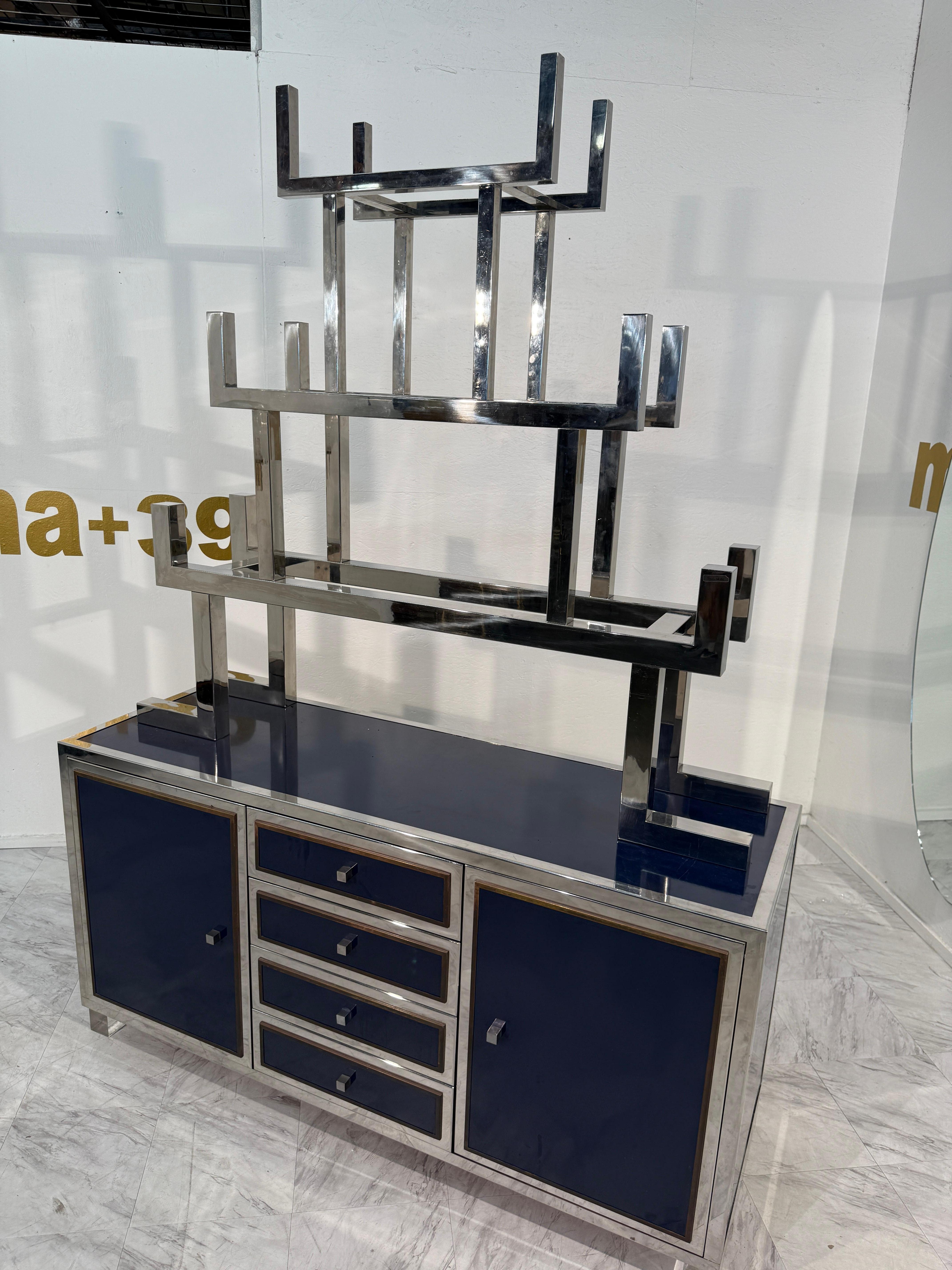 Striking Italian mid-century modern credenza with integrated bookshelf, dating to the 1970s. This sculptural piece combines a bold geometric chrome frame with deep navy blue lacquered panels, resulting in a sleek and sophisticated design.

The lower