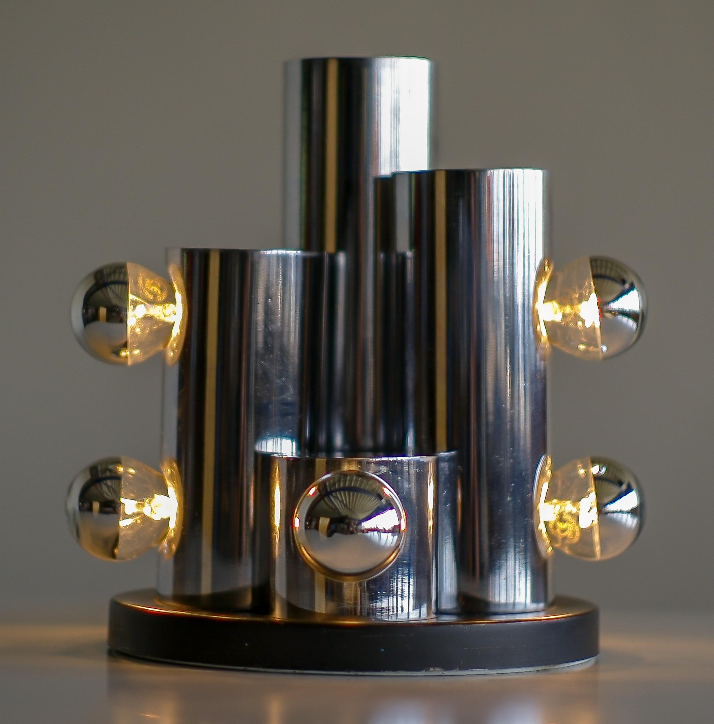 Italian Mid-Century Modern table lamp with eight chrome light bulbs.
Chromed steel cylinders with 1, 2 or 3-light sockets on a black enameled steel circular base.
Wired for use in the USA.

The design has many characteristics of Arredoluce, but