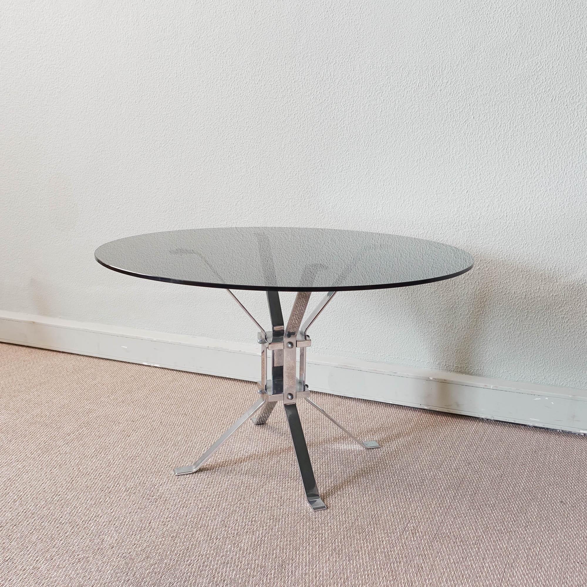This coffee table was designed and produced in Italy during 1970s. The structure as a central foot and is made of chromed steel legs with the top in smoked glass. The glass top is original, and one of the rubbers, that protect the glass from the