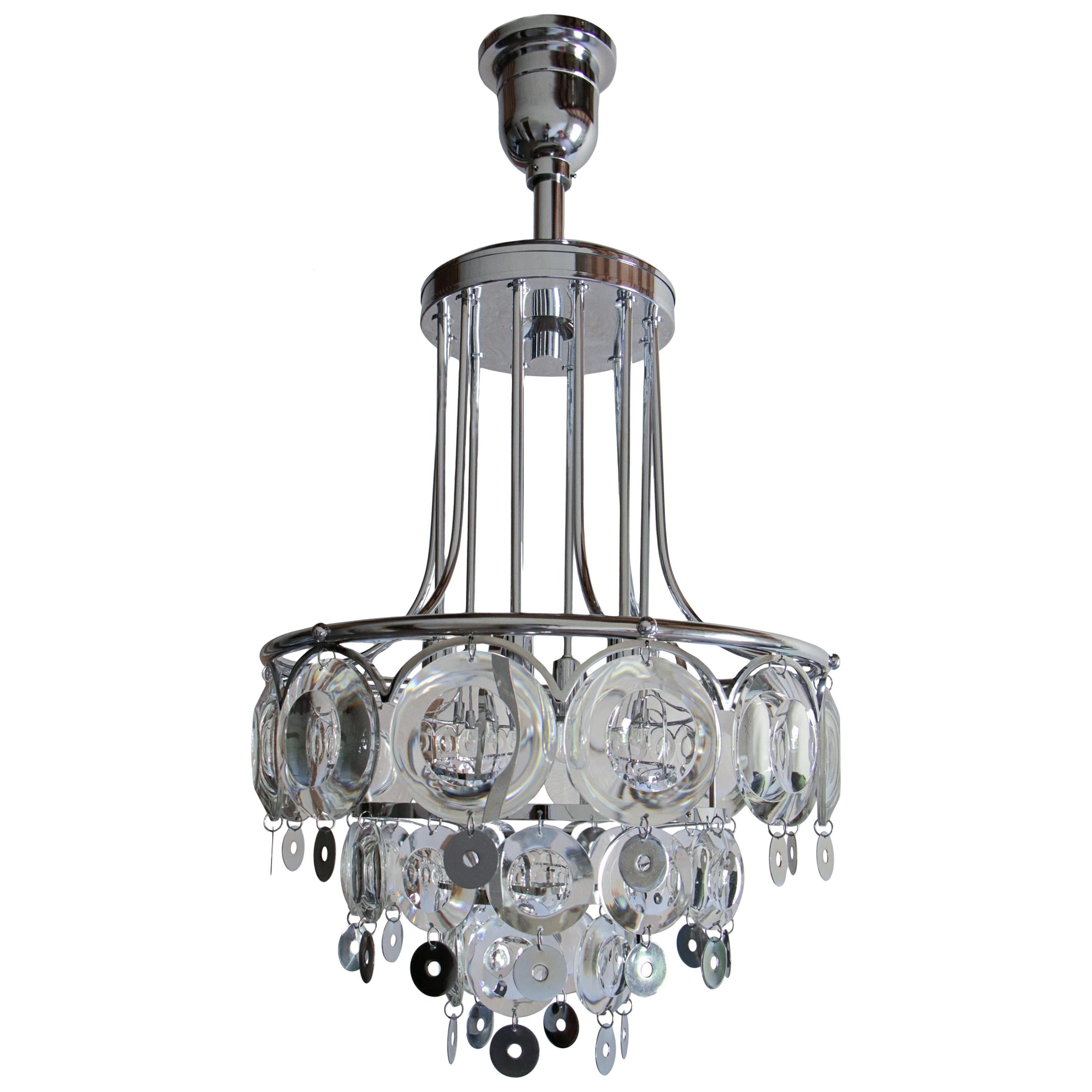 Splendid Italian chromed chandelier from the '70s, attributed to Oscar Torlasco. Structure made of chromed brass, chromed steel, and lenticular glass. Six functional lights, E14 format. An elegant and decorative piece of furniture, capable of giving